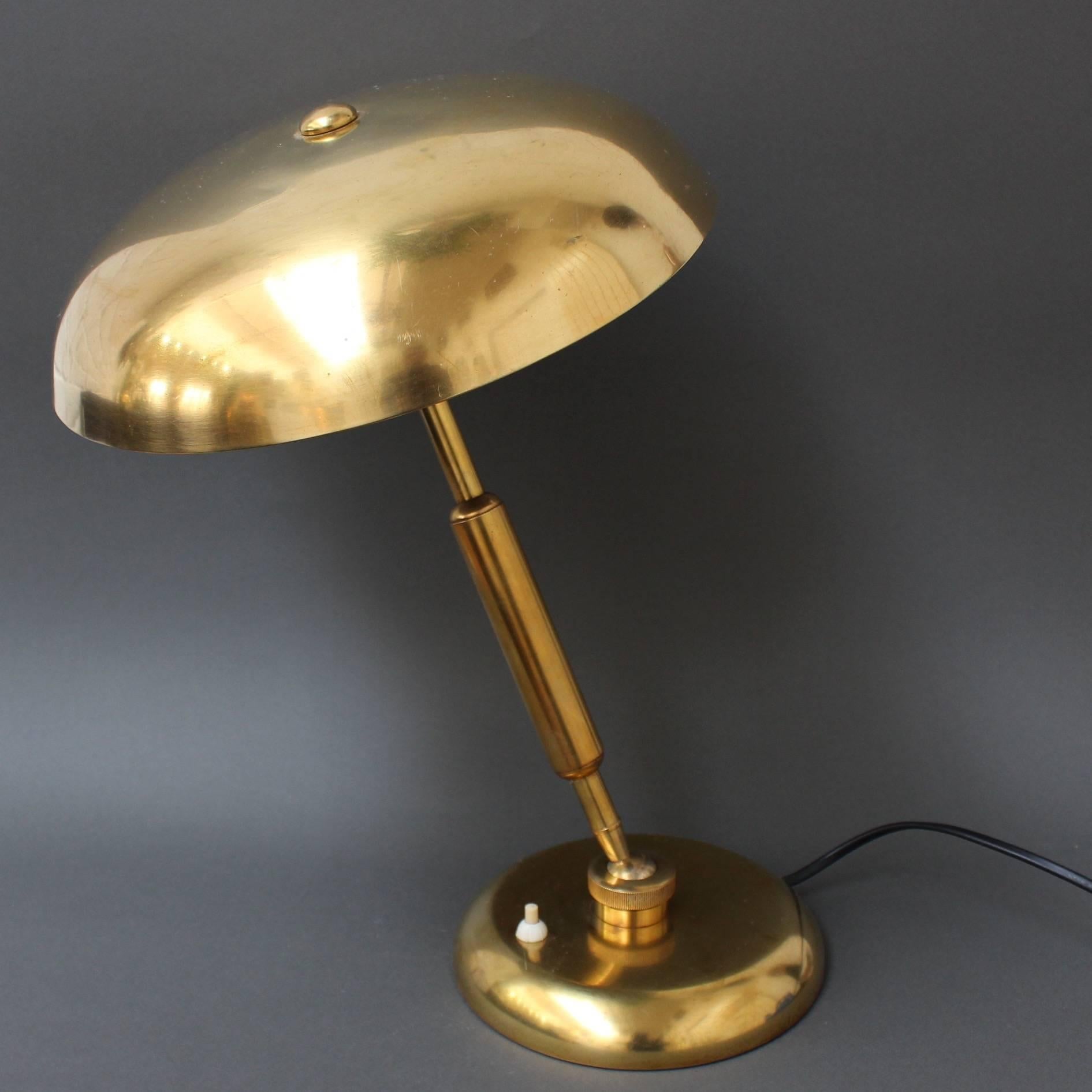 Pre-war Italian brass desk lamp, circa 1940s. A classic desk lamp which combines the characteristics of the Art Deco and Art Nouveau movements. A Lariolux ministeriale rounded shade tops an adjustable brass support stem. The brass features a
