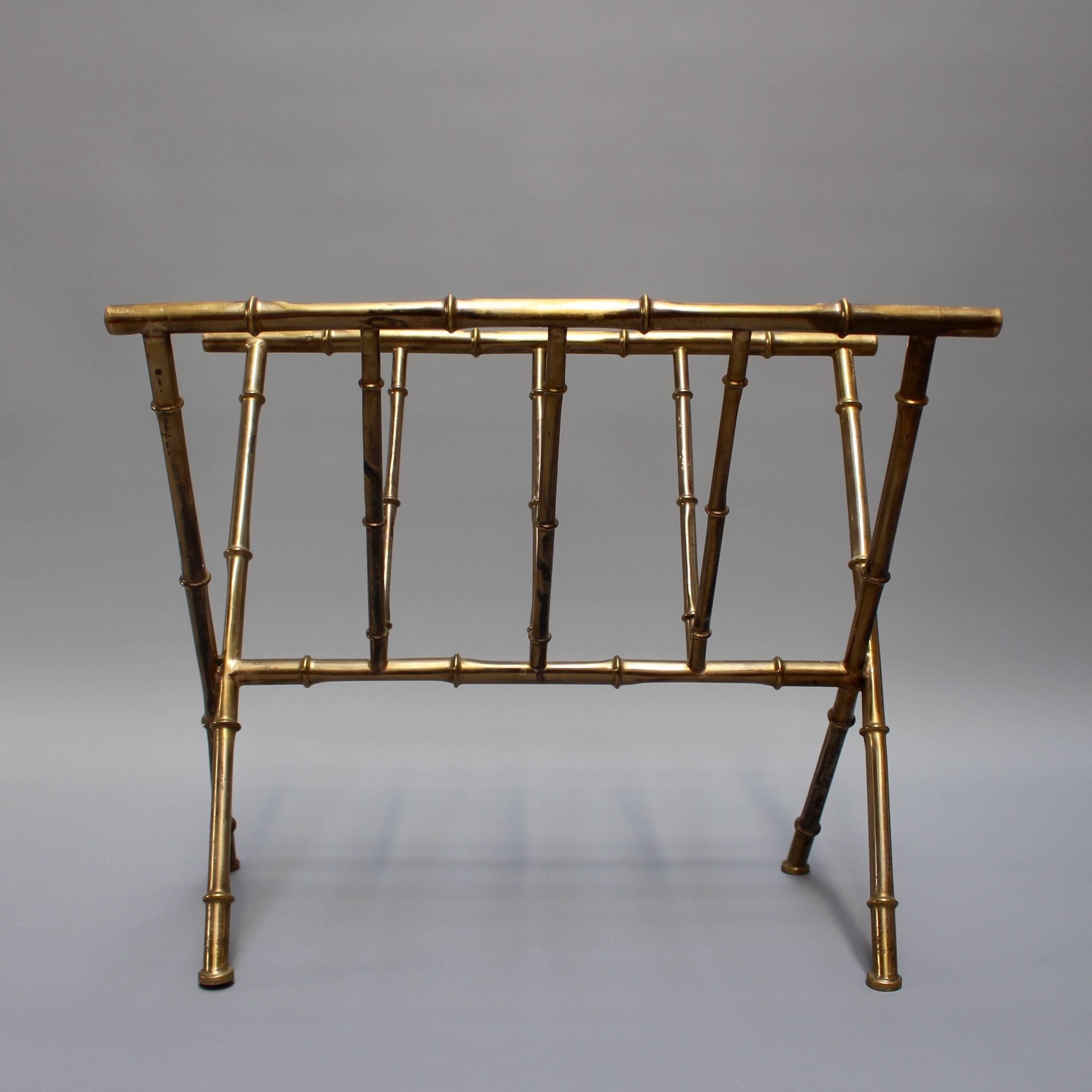 Brass 'bamboo' magazine rack, circa 1950s in the style of Jacques Adnet. Functional beauty in its essence - V-shaped cross-legs in polished brass and in good vintage condition commensurate with its age and function. Some visible blemishes and other