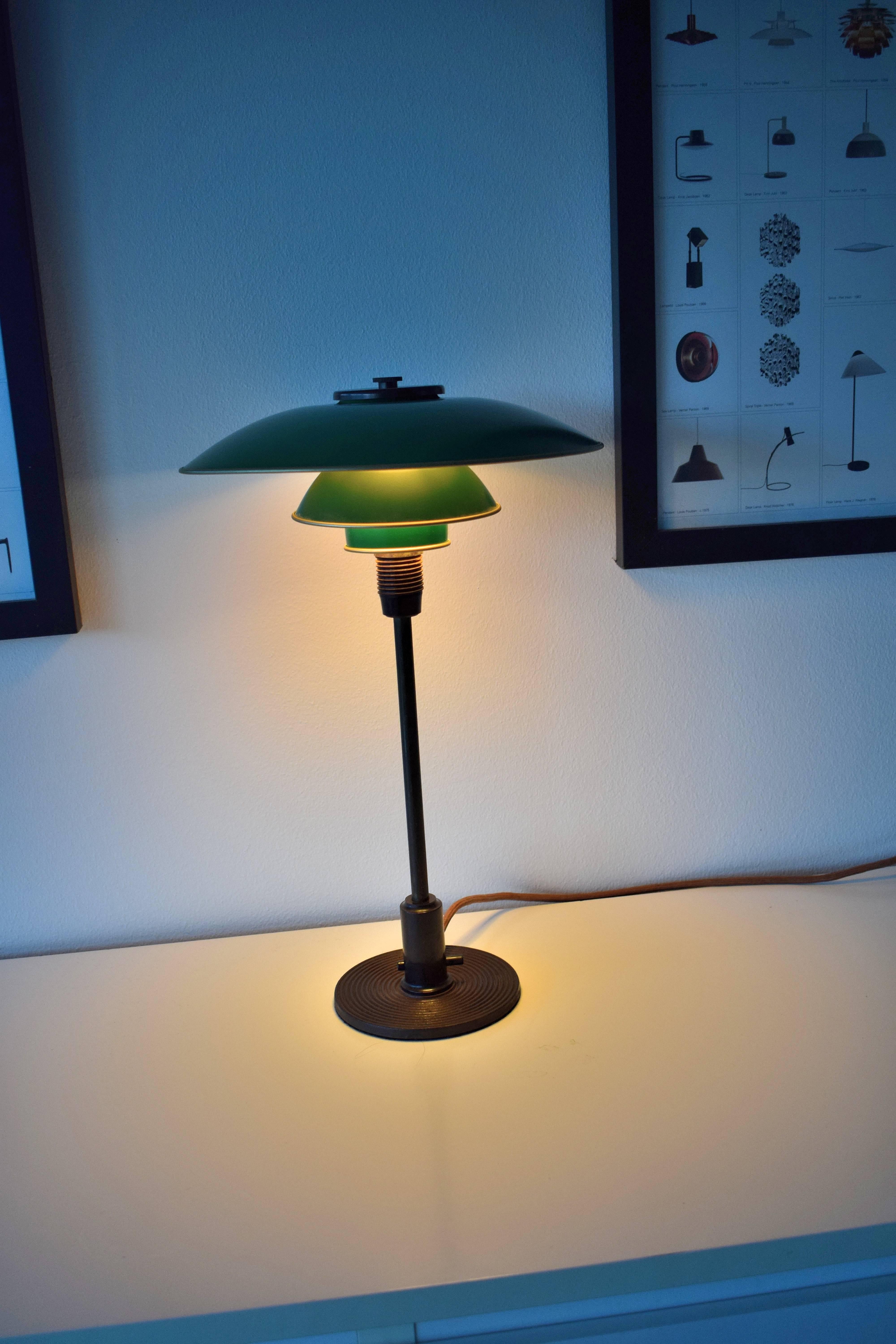 PH 3/2 table lamp by Poul Henningsen. Green metal shades patinated brass stem and Bakelite detailing. Through-switch of bakelite
Manufactured by Louis Poulsen in Denmark, circa 1930.