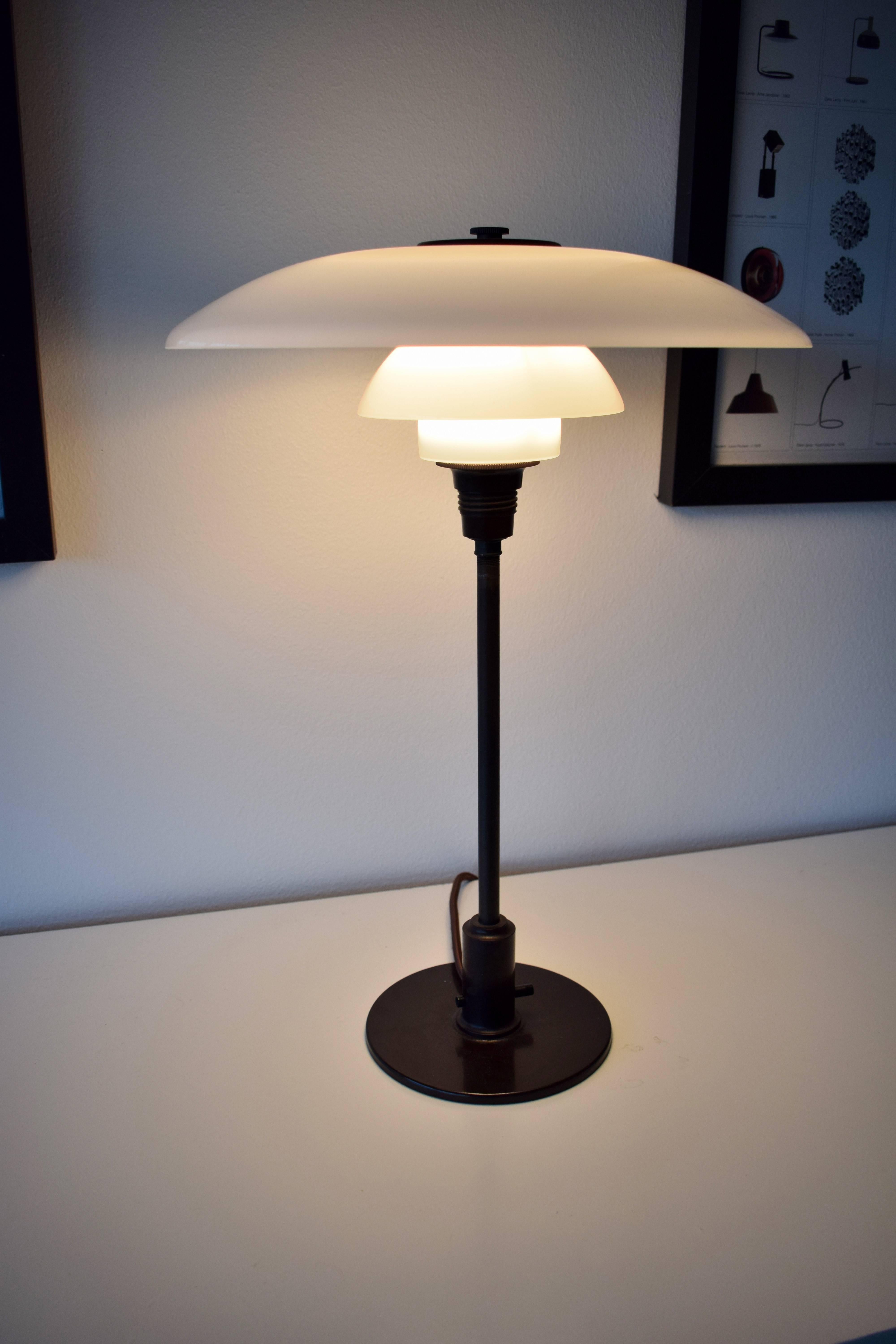 PH 3½-2 table lamp by Poul Henningsen. Opaline glass shades, patinated brass stem and Bakelite detailing. Through-switch of bakelite.
Manufactured by Louis Poulsen in Denmark, circa 1930.