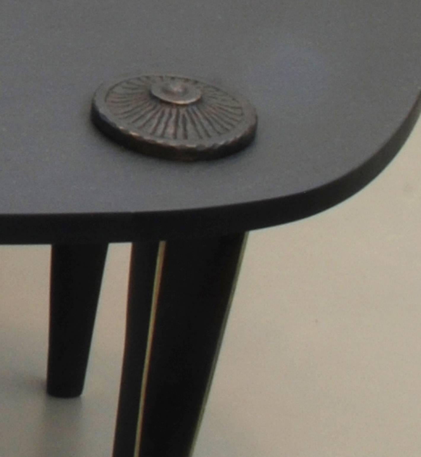 The piece is composed of two triangular tables.
Each table has three bronze legs; with a combination of polished bronze and black patinated bronze.
A bronze decorative stud sits atop each point of attachment to the legs.