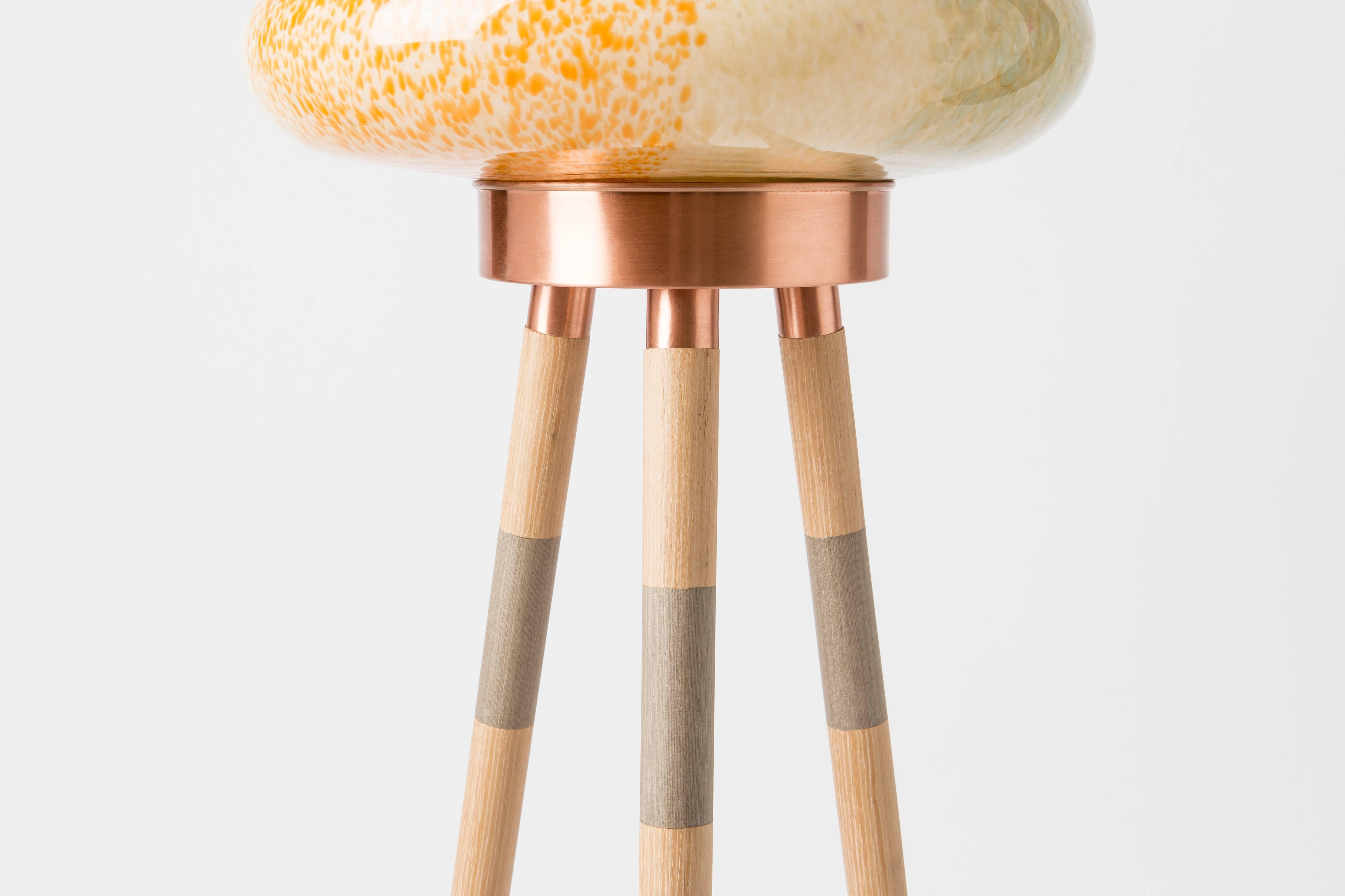 This beehive inspired floor lamp comprises a mixed colored hand blown glass shade and different combinations of wood veneer legs and copper. The light is adjustable by the dimmer. 

Materials: hand blown colored glass lampshade, polished copper