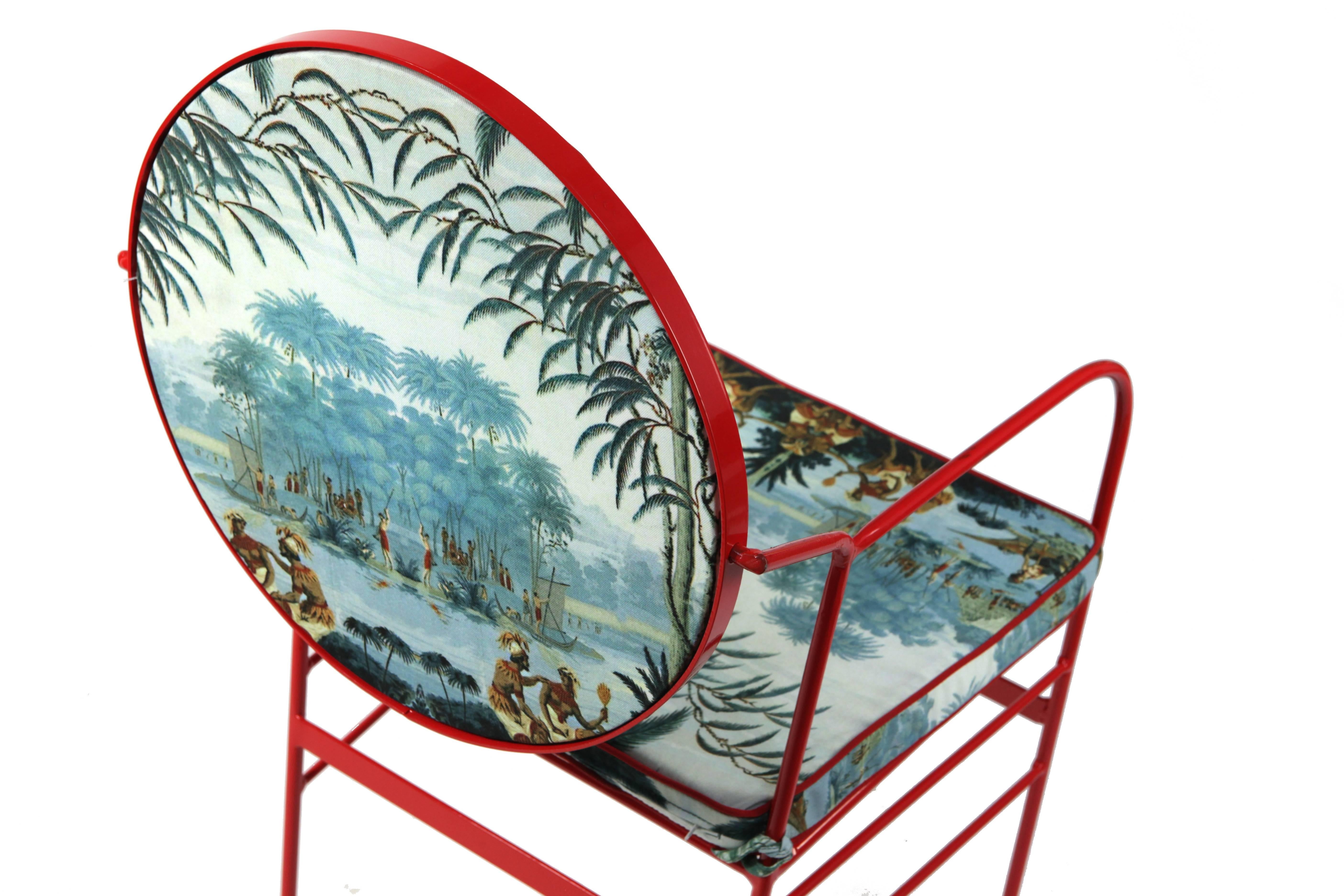 The iron structure of this striking chair was dust-painted in a vivid shade of red, the same found on the piping along the edges of the two cushions, printed on sturdy and yet soft man-made fabric with a pattern inspired by 19th century panoramic