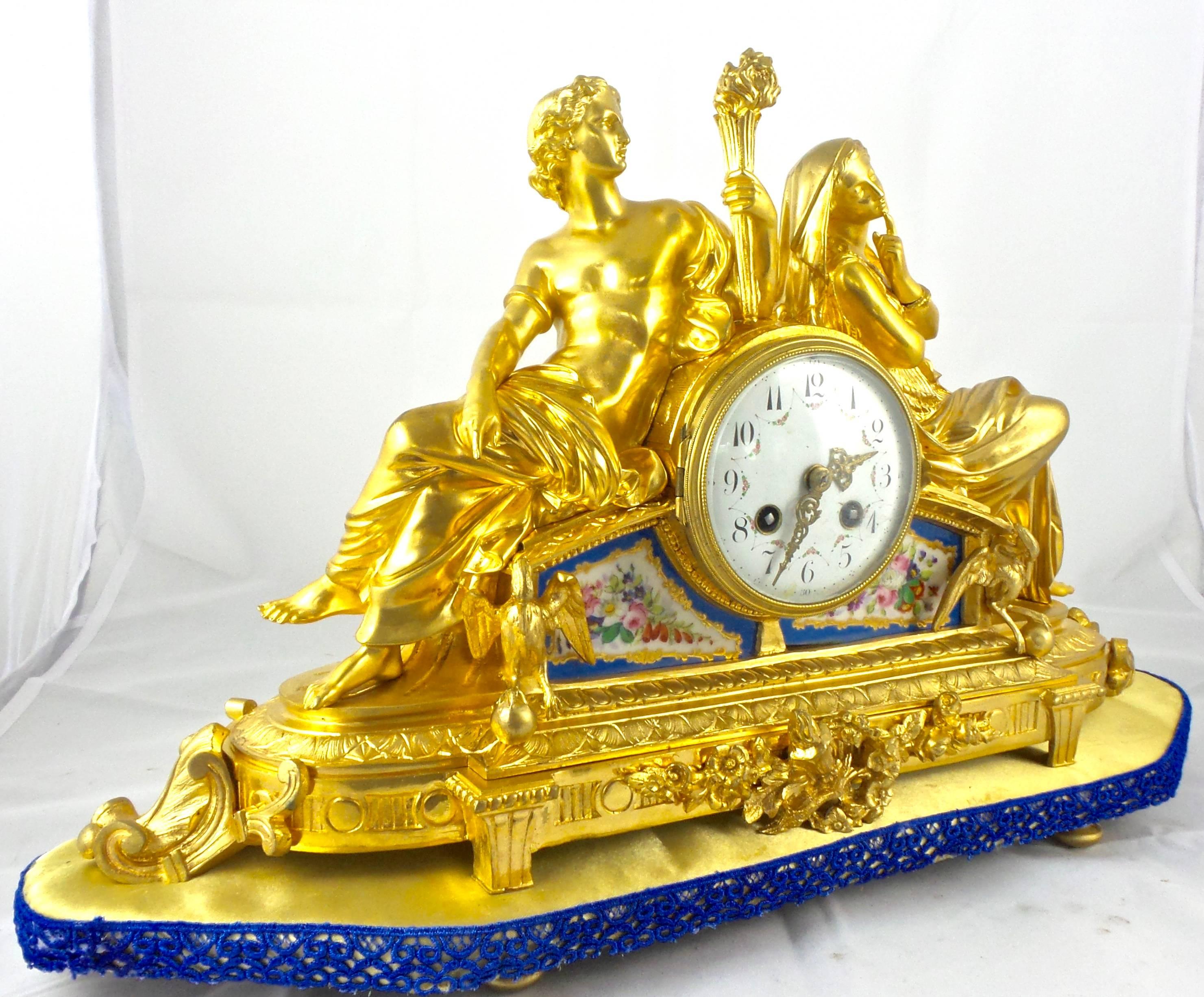 19th century French classical mantel clock of very high quality
Gilt ormolu bronze with hand-painted Sevres porcelain
Romantic classical figure with fire torch and figurine on top and other fine adornments and designs
Coming on a base
Convex