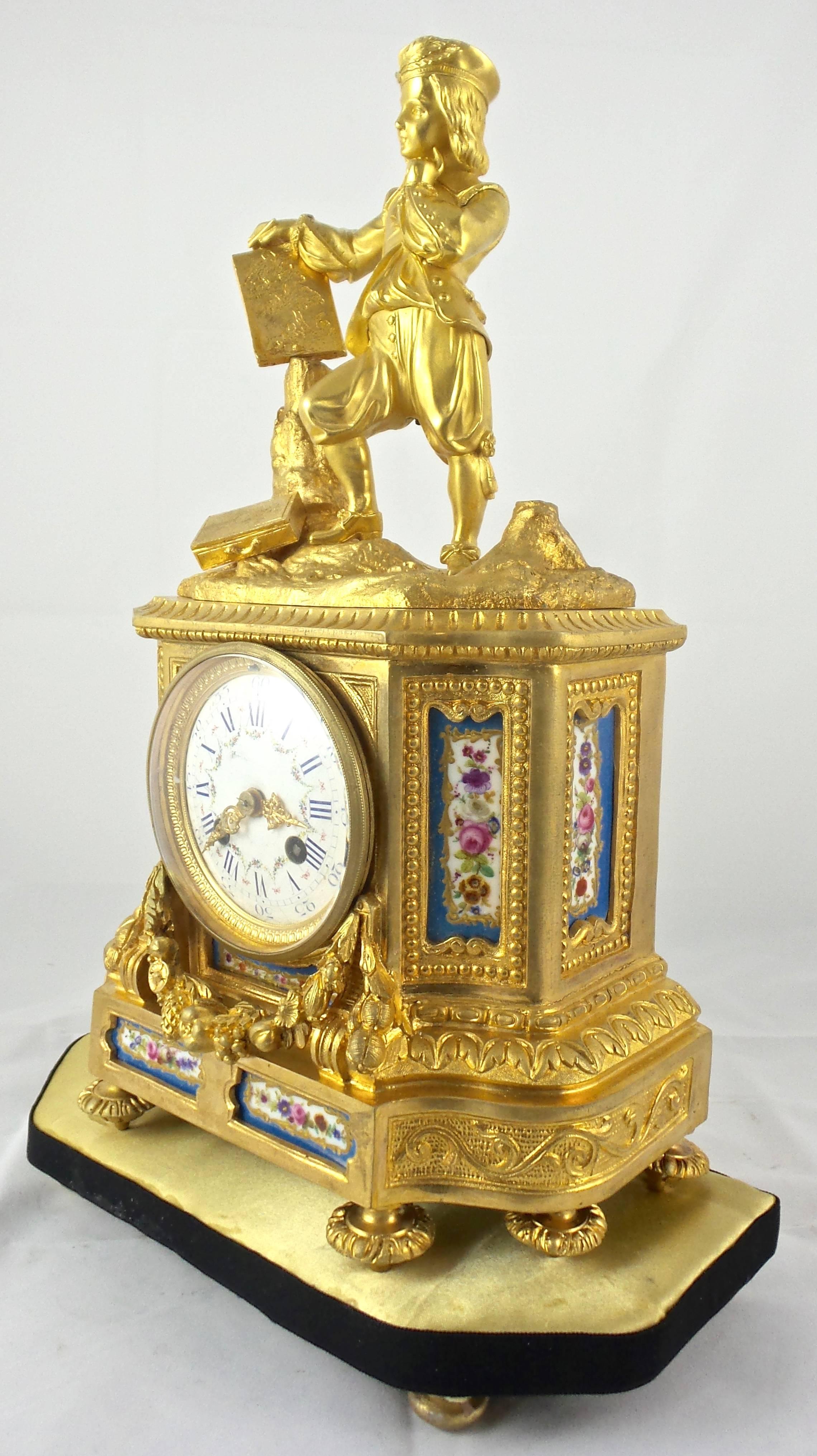 Gilt ormolu bronze 19th century French mantel clock with blue Sèvres porcelain
Figural gent standing on top with fine detail and posture
Draped vines and other adorned patterns
Standing on a base
Convex floral painted porcelain dial and bevelled