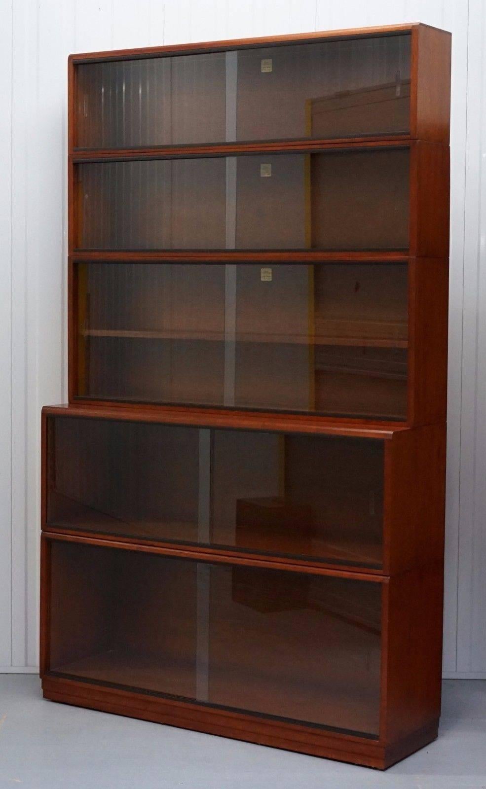 We are delighted to offer for auction this stunning five-piece stacking 1960s section bookcase fully stamped and labeled by Simplex in medium Mahogany and finished with glass sliding doors

A great find in excellent period condition, the glass is