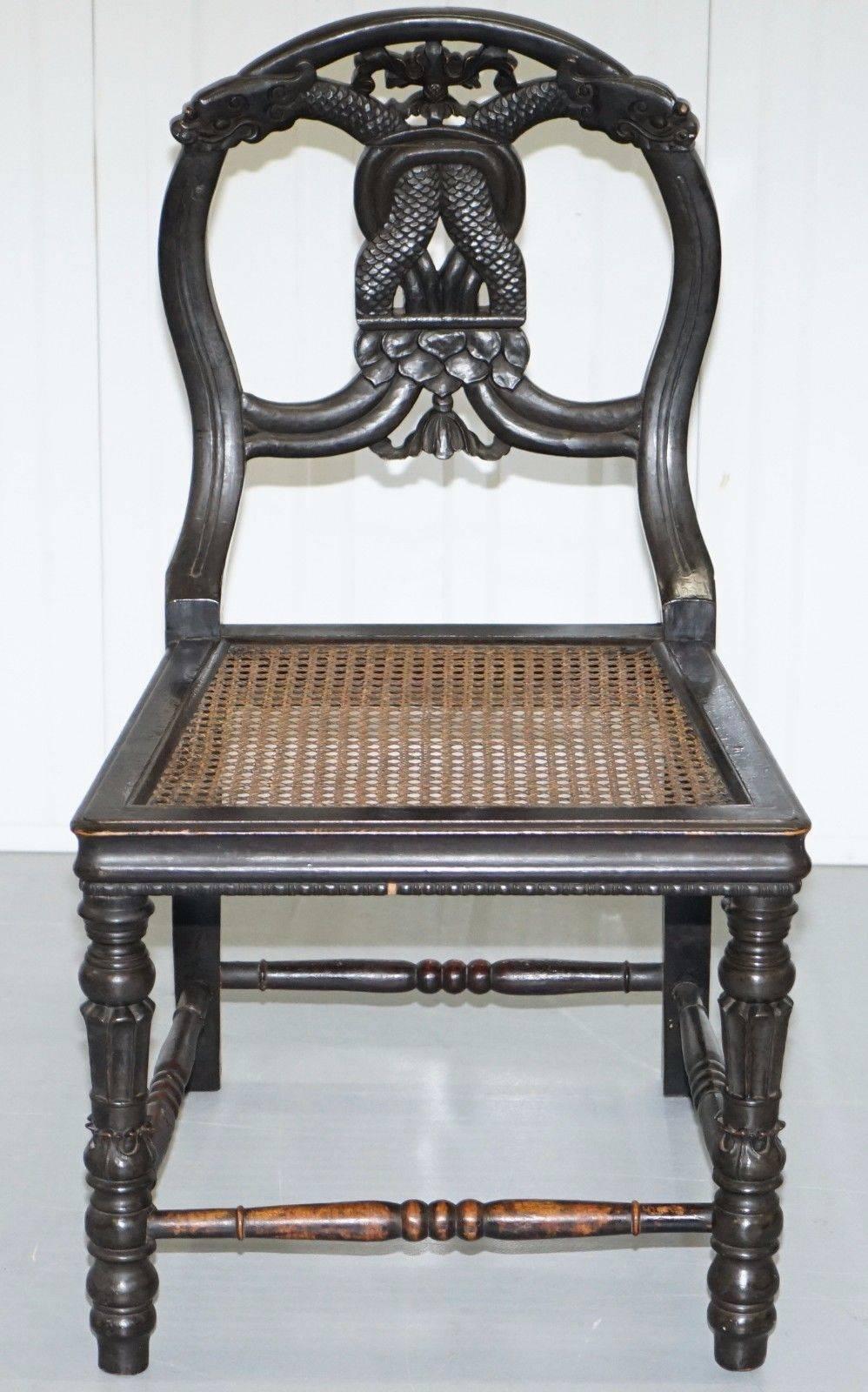 We are delighted to offer for sale this stunning set of four 19th century hand-carved dragon head ebonized black chairs with bergere bases

A very rare set in stunning unrestored period condition throughout, the bergere or rattan is all completely