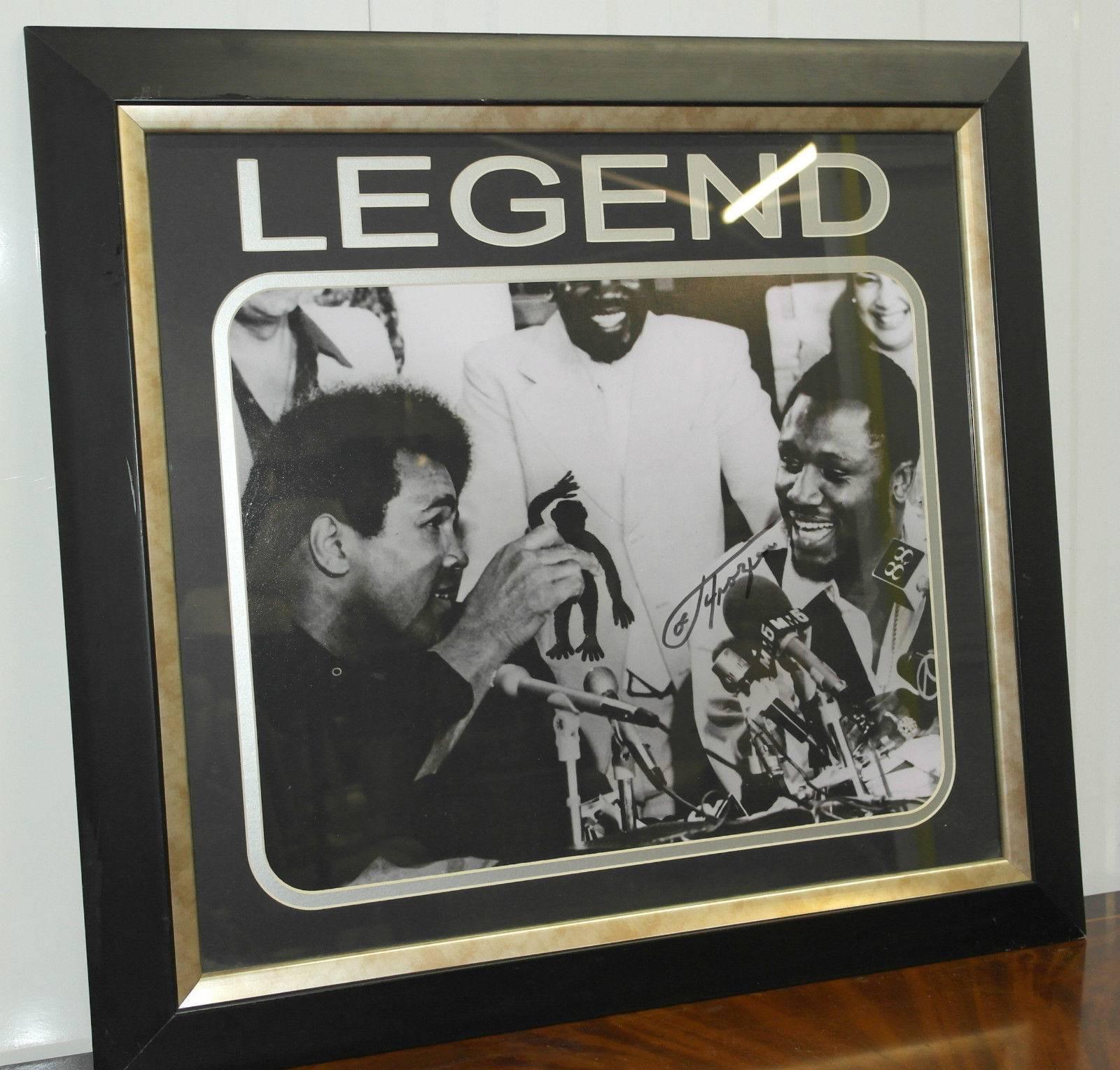 We are delighted to offer for sale this stunning and really quite rare original signed Joe Frazier with Muhammed Ali “Legend” print

The signature is original, signed well in black marker

A black and white photograph featuring Muhammad Ali and