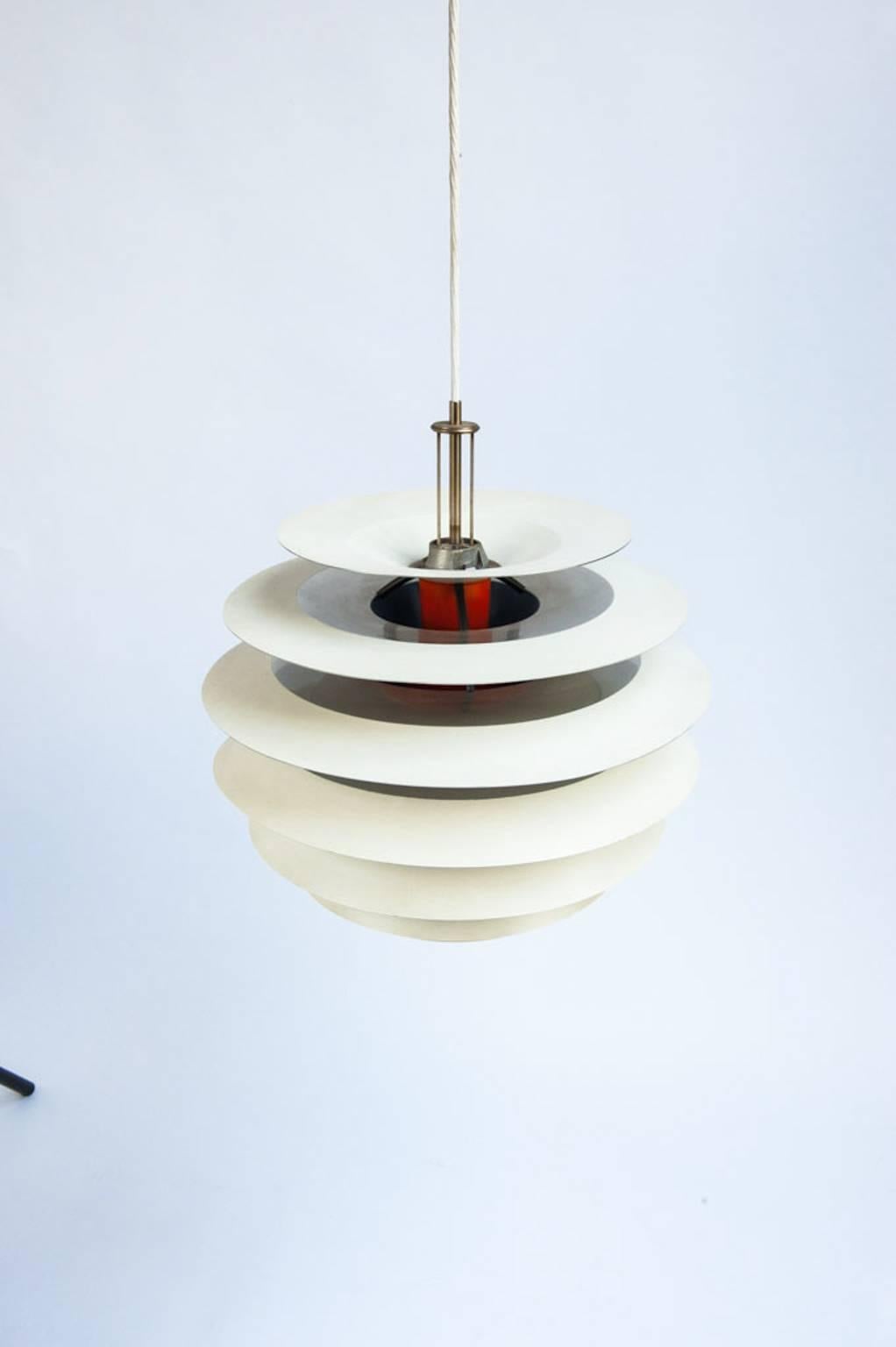 The beautiful contrast ceiling lamp was designed by Poul Henningsen and manufactured by Louis Poulsen during the 1960s in Denmark. The lamp features a white and orange lacquered metal structure with chrome details and black lacquered brass fittings.