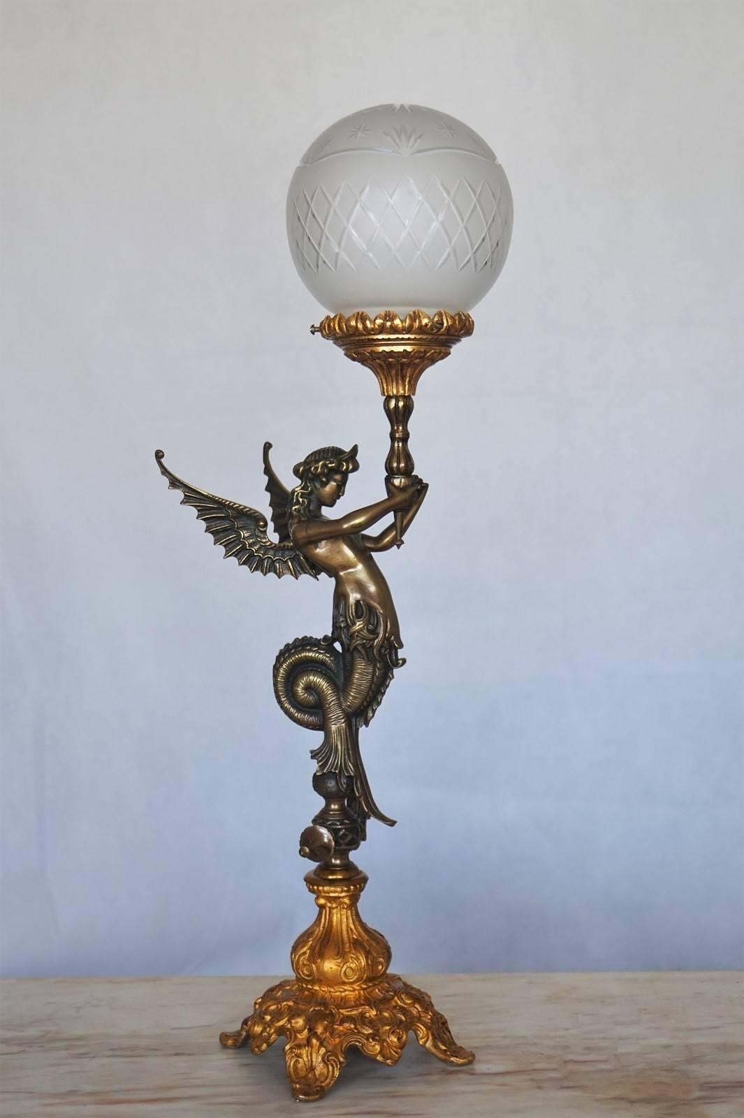 Late 19th century Empire style winged figural bronze table lamp with gilded bronze base and lamp holder, with crystal ball shade.
This piece has been electrified at a later time.

Height with shade: 24 1/2 in (62 cm)
Height without shade: 19 1/4 in
