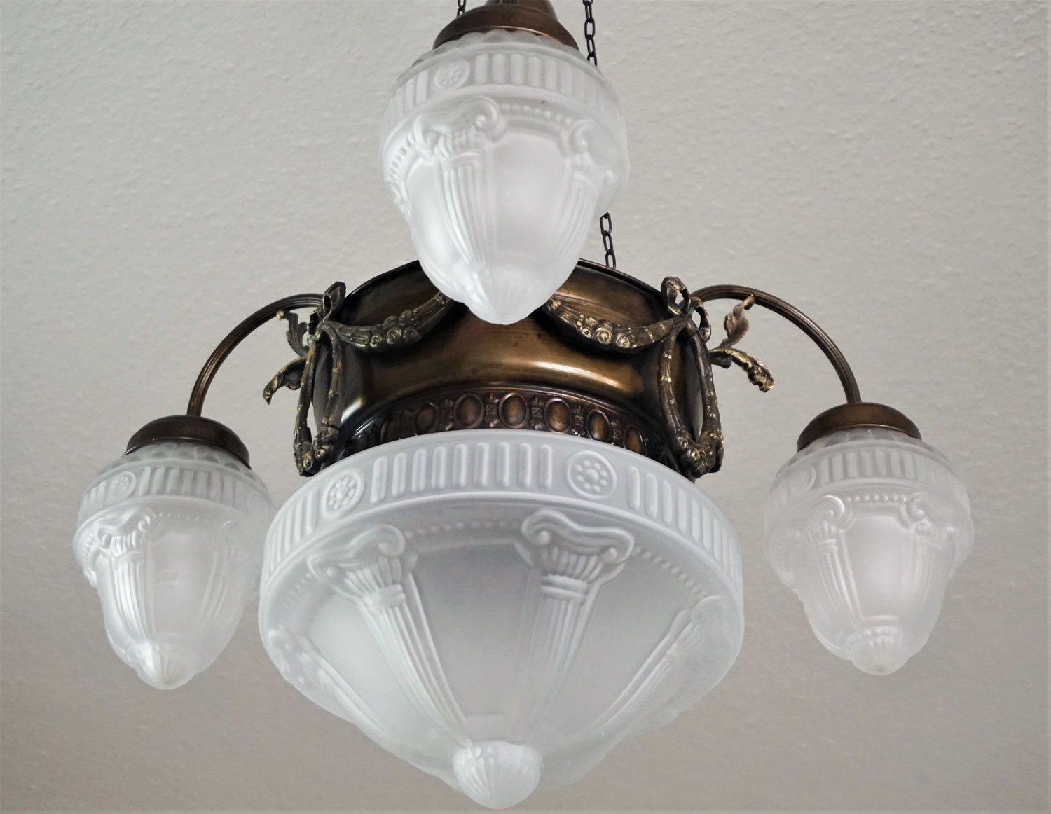 French Art Nouveau brass four-light chandelier, pendant with frosted glass globes, circa 1920.

European wiring: Three E14 light sockets (lamp arms) and one E27 light socket (in the middle) 

Measures: Height 33 ¾ in / 86 cm
Diameter 22 in / 56