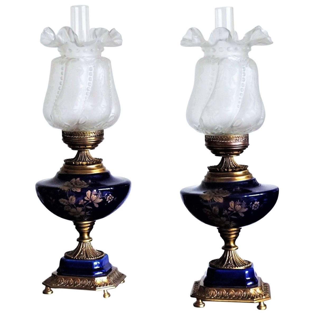 Pair of Italian vintage cobalt blue porcelain and brass vase table lamps, on one side hand painted gilded floral decor, with high relief etched glass shades and glass chimneys, circa 1960

Very good condition, no chips or cracks, brass with signs