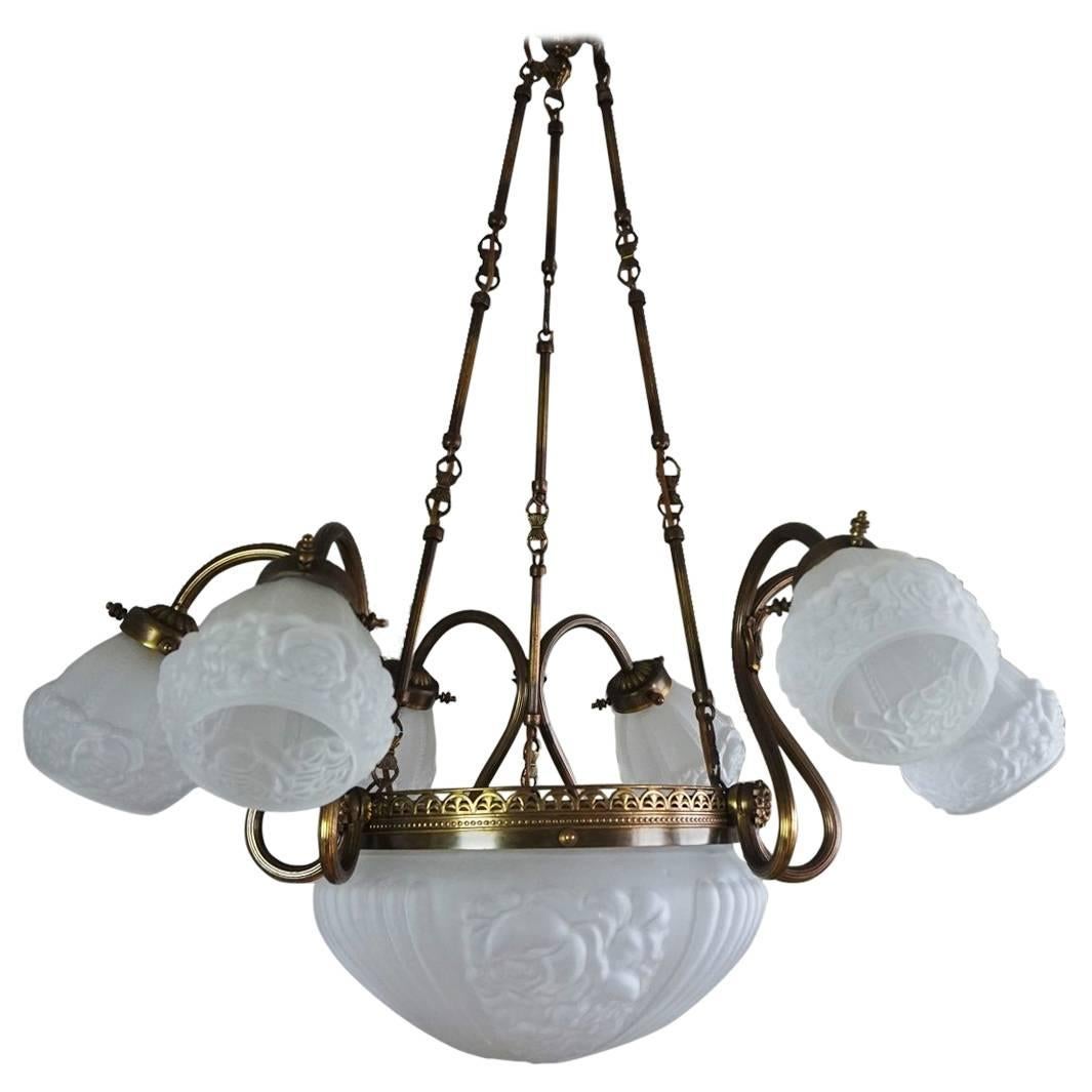 Midcentury brass nine-light chandelier with large frosted glass in high relief bowl shade surrounded by a crown-like band, six curved lamp arms with frosted glass in high relief shades, circa 1930-1940.
Number of lights: Nine E14 bulb