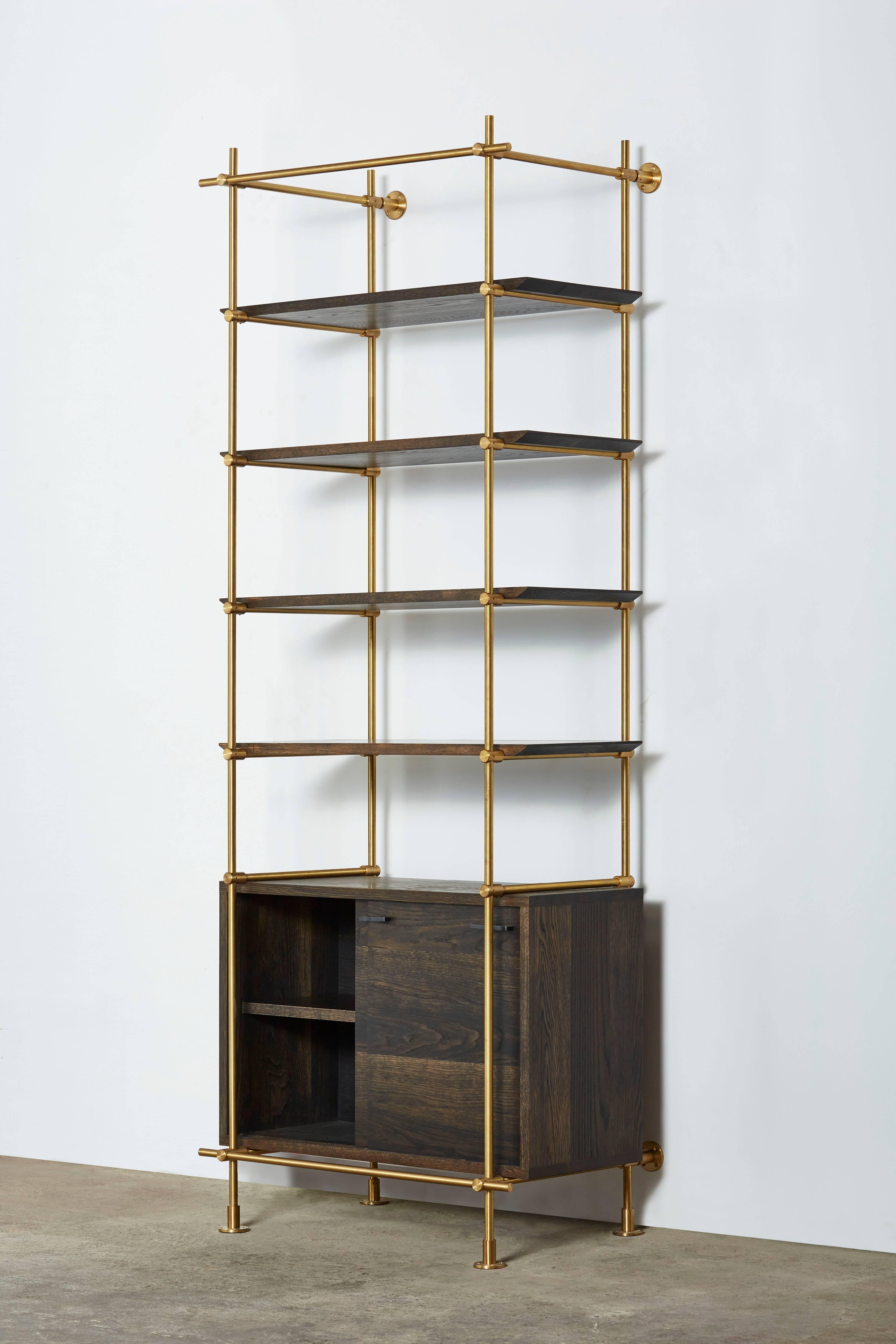 This single bay version of Amuneal’s collector’s shelving unit features solid machined brass fittings and posts in a warm brass finish. The unit mounts to the floor and to the wall to support a series of easily adjustable shelves and credenza
