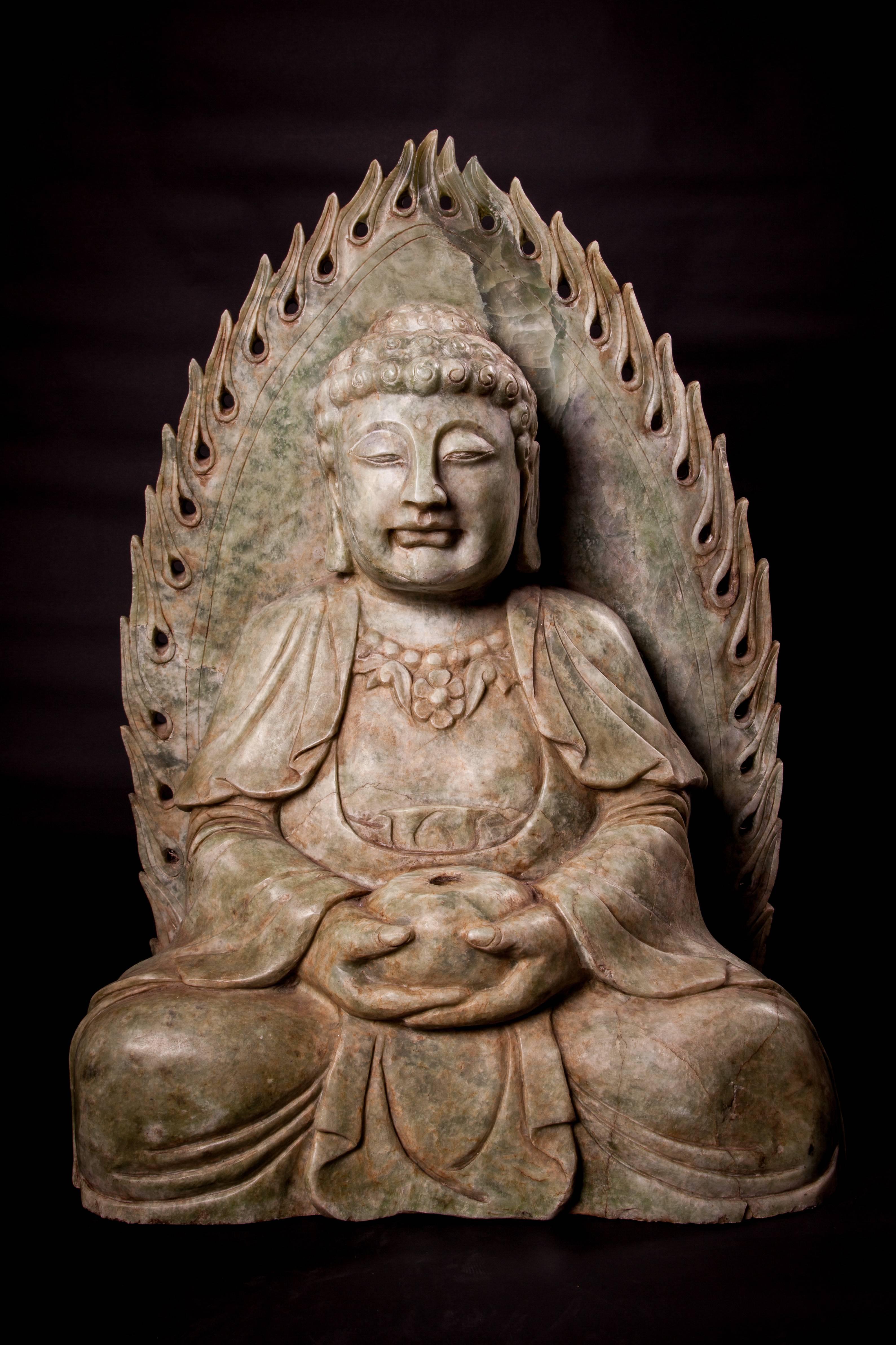 A Chinese carved jade statue of a seated Buddha holding a pot, eyes closed, a flaming lappet behind,

The Shakyamuni Buddha, better known as Siddhartha Gautama, is often depicted sitting holding a candle or a bowl.