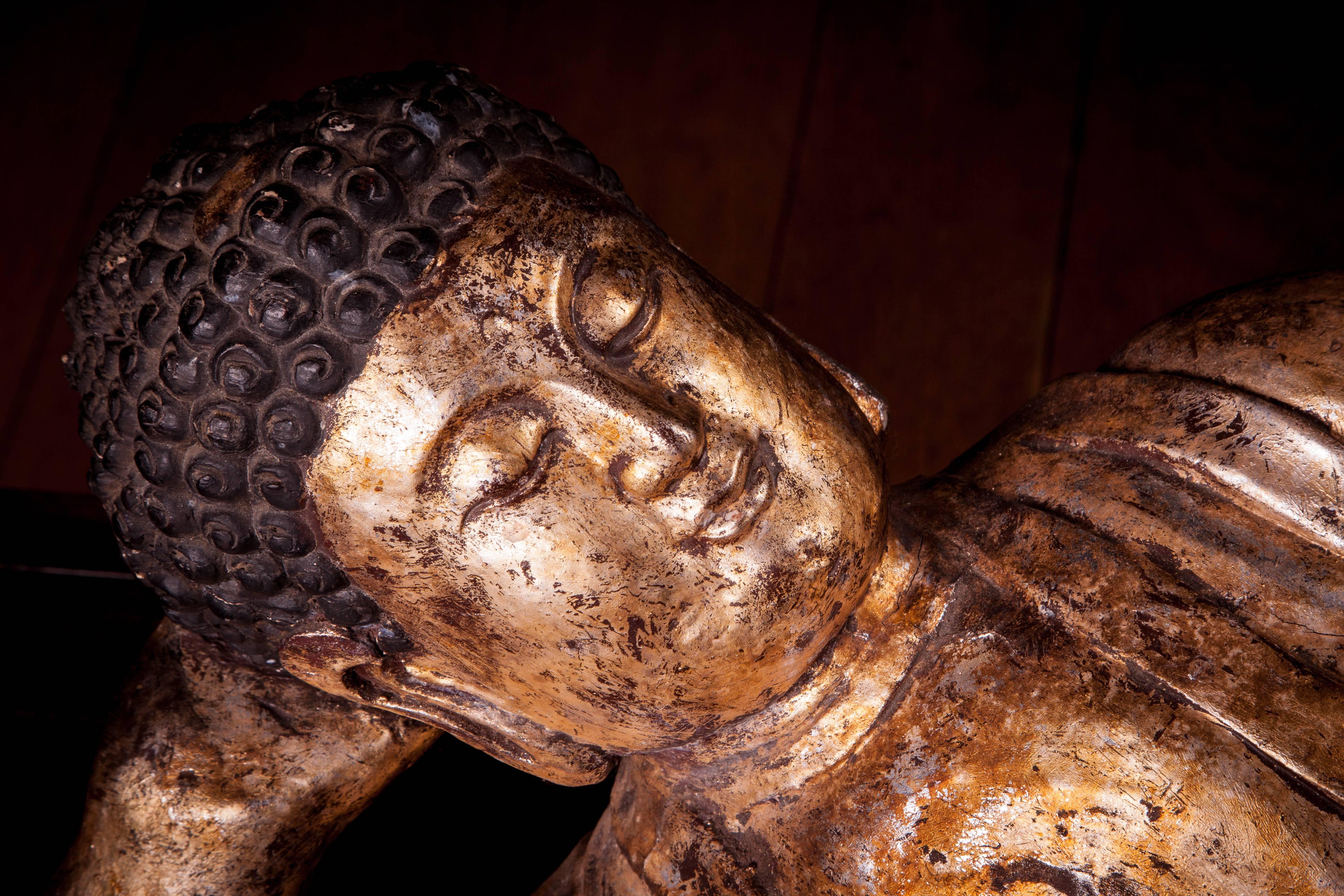 Chinese giltwood reclining Buddha Old Chinese gilt and carved wood Buddha in repose, resting on his right arm with tightly curled hair.