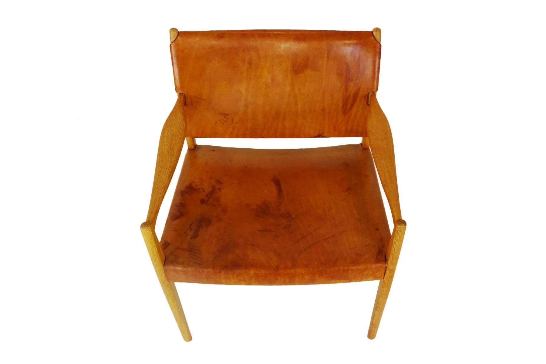 A Classic midcentury armchair designed by Per-Olof Scotte in heavy cognac saddle leather with oak frame. Well, you either love your leather in an unmarked condition or you prefer it with age related patina. If you prefer the latter (and there is no