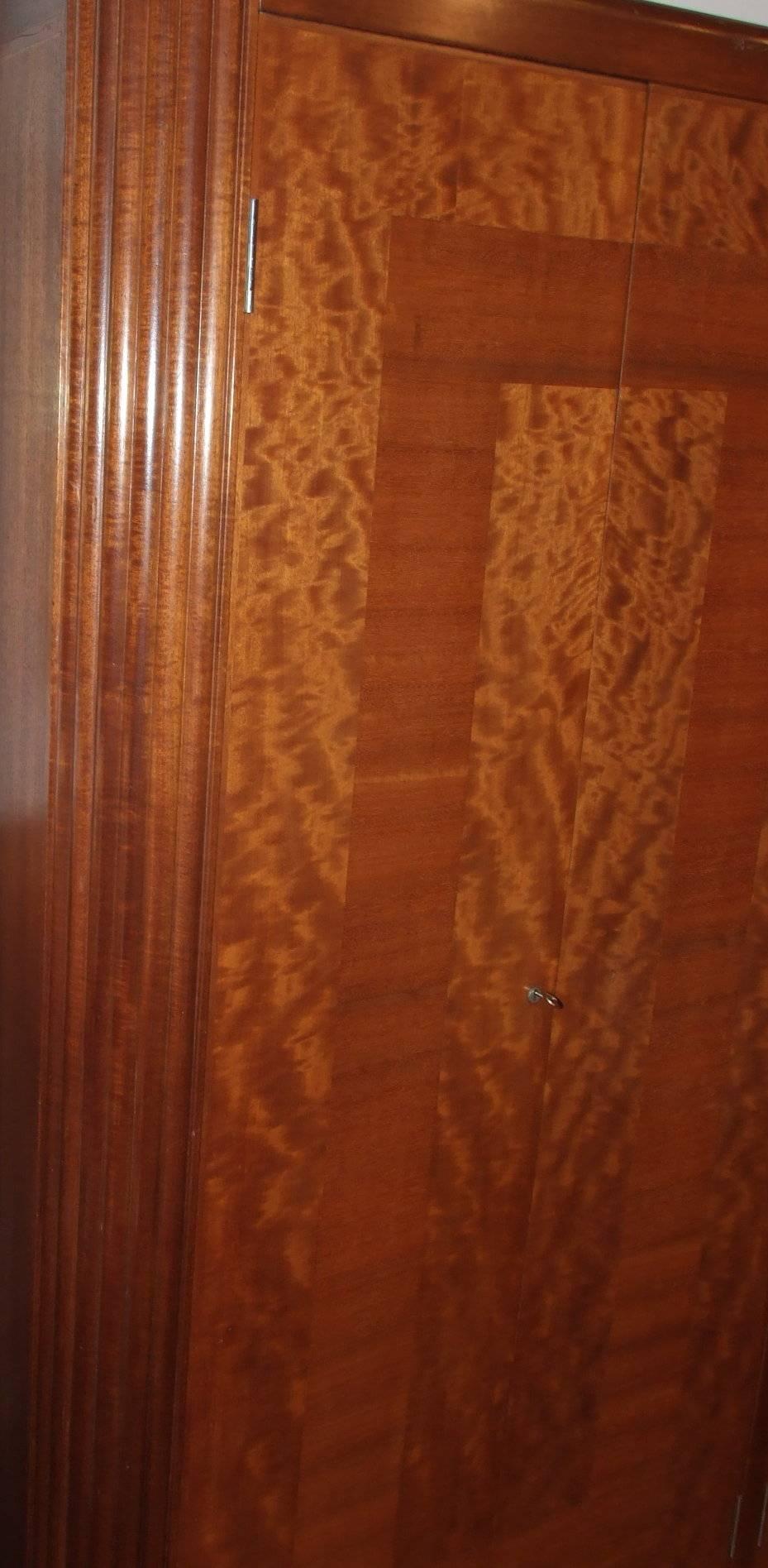 A Queensland walnut and cherry mahogany (makore wood) unusual four door wardrobe with reeded edges on stained plinth, cross-banded pattern to the doors, the interior of tongue and groove cedar (stamped Little Rock Arkansas) with dowel supports for