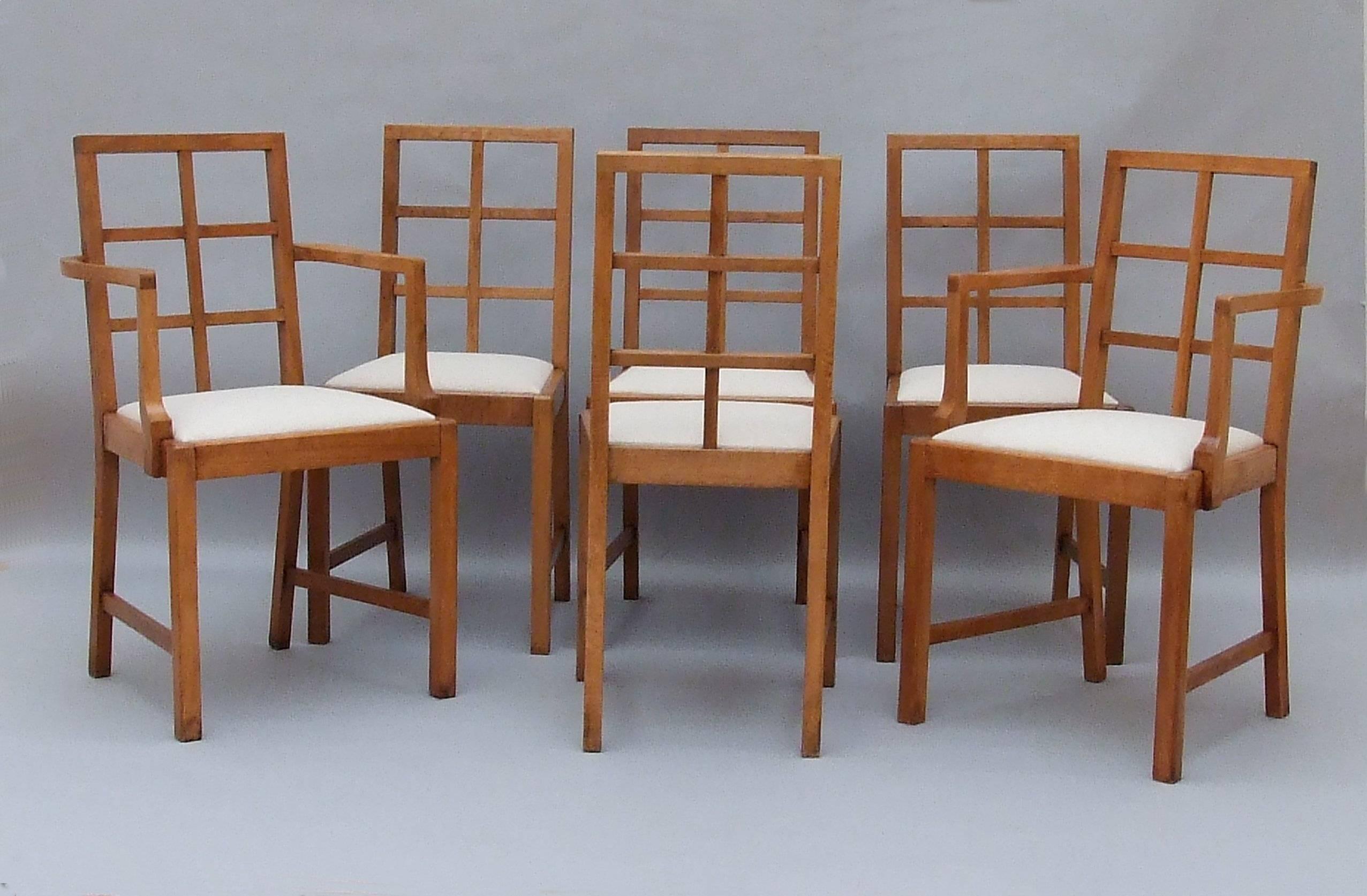 Attributed to Heals Set of Cotswold style oak lattice back dining chairs, two arms, four sides, with chamfered frame and legs and with drop in seats re-upholstered in linen, circa 1925, 90cm (35.5in) high, seat height 48cm (19in).
