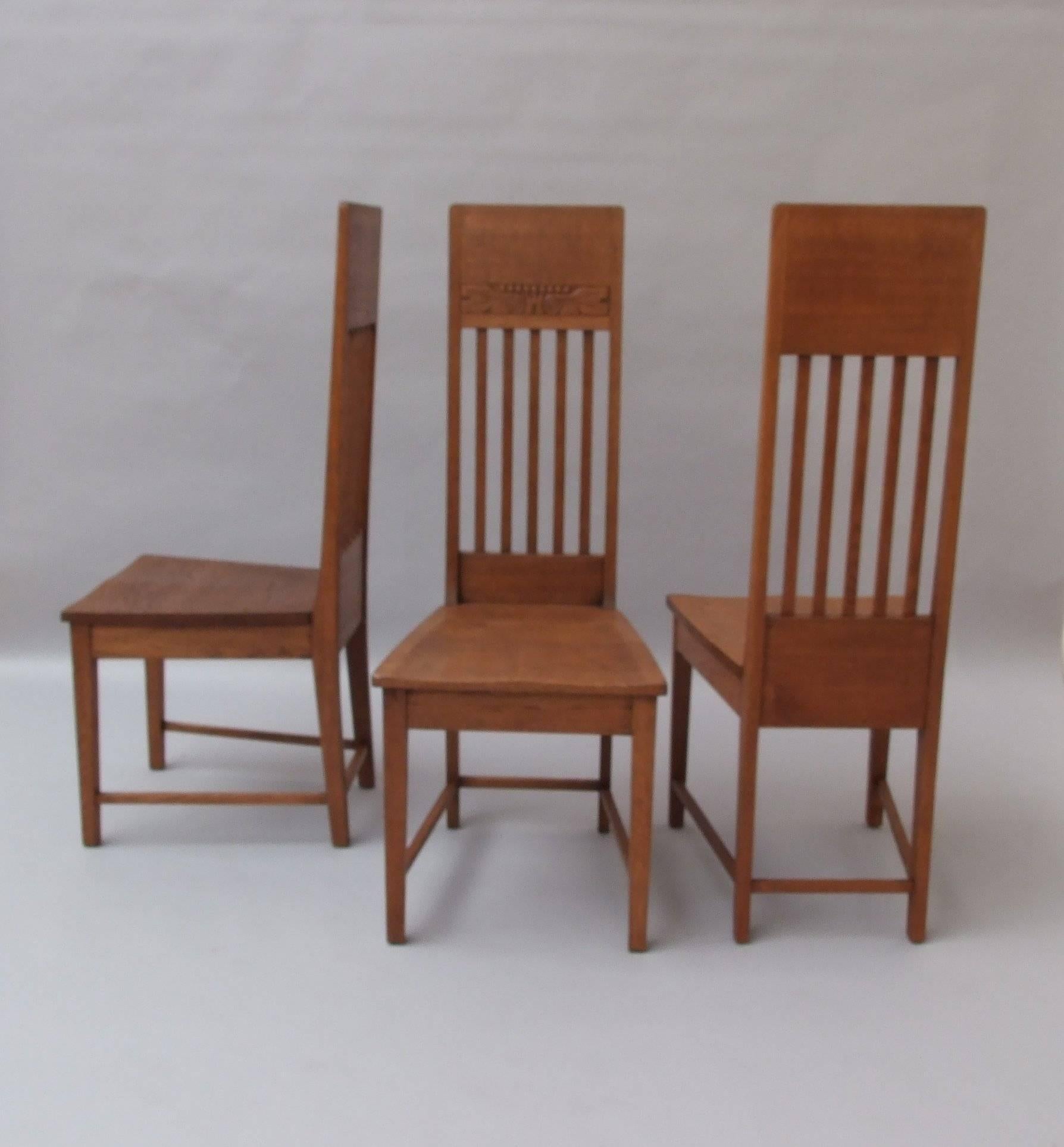 A set of eight oak Glasgow style high back side dining chairs, with shaped seats and slat backs and with stylized oak leaf and castle design carved to the wide top rail, circa 1900. Measures: 115.5cm (45.5in) high, 46cm (18in) wide.