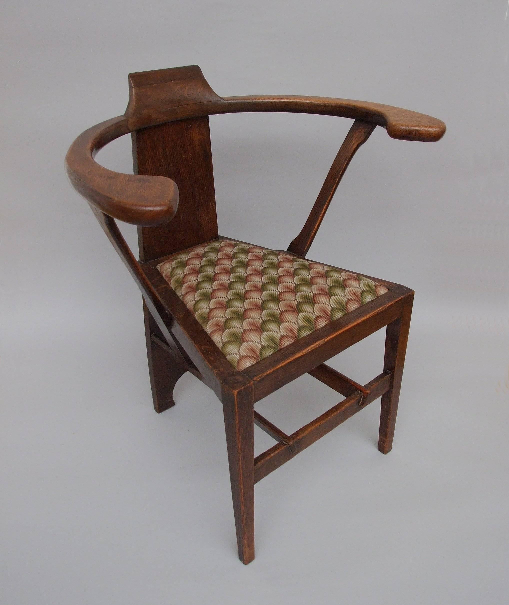 An oak Glasgow style chair with cantilevered arms, shaped supports and through back splat, drop-in upholstered seat, after a design by George Walton, a variant on the Abingwood range as designed for Miss Cranston's Buchanan Street Tearooms and for