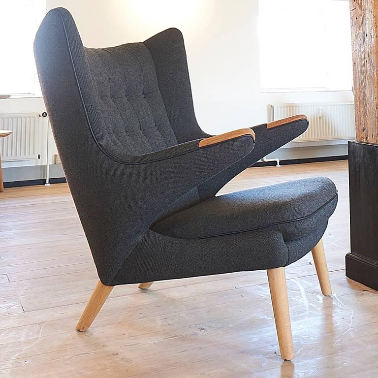 Hans J. Wegner AP19 Papa Bear chair in dark grey Hallingdal wool, code 180 and with black leather chains and buttons. 

Legs and nails in oak.