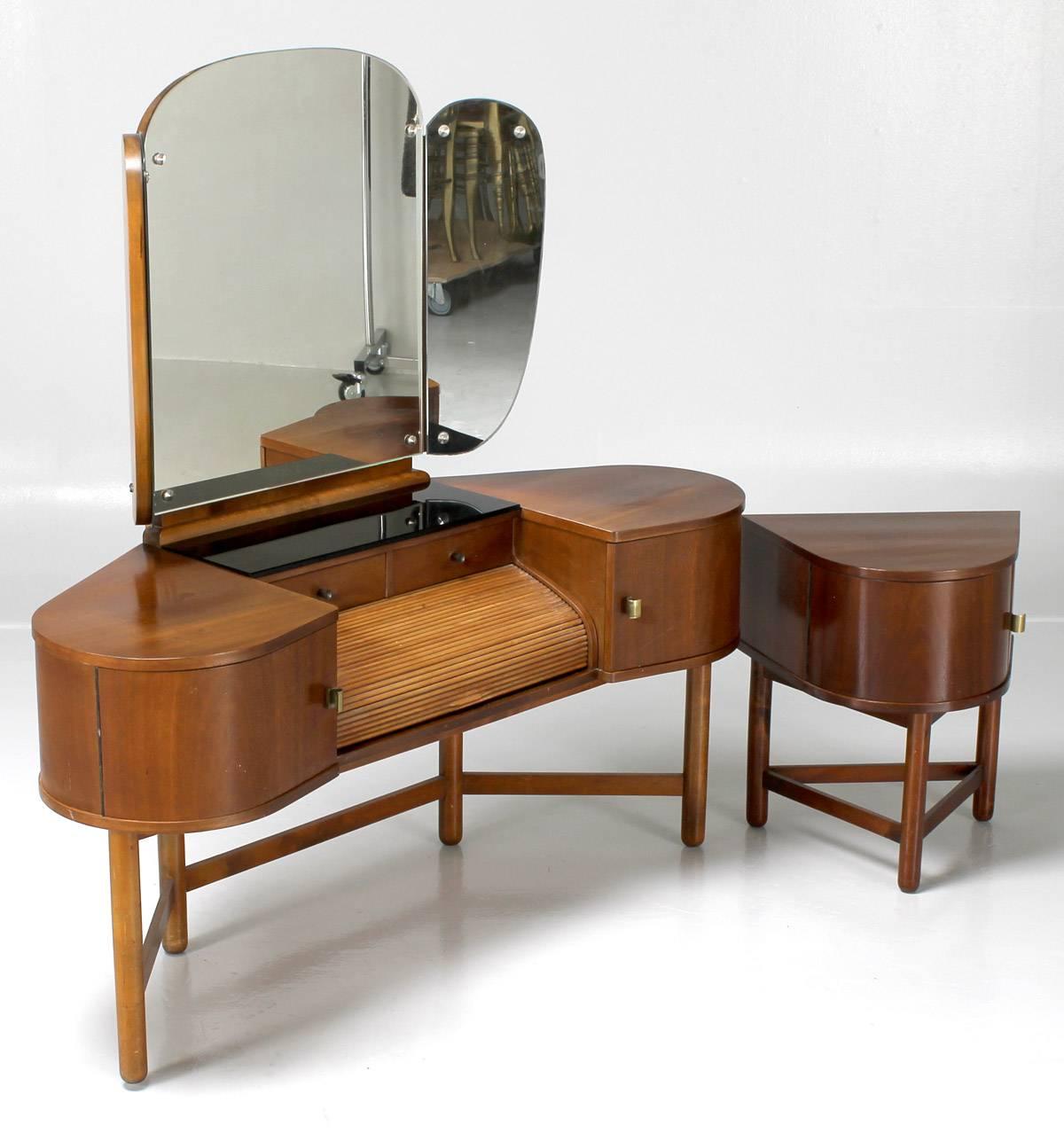 Vanity table and occasional table produced by master cabinetmaker Martinus Petersen, Denmark, 1930s.

Mahogany with tambour door and black glass panel. Three-section mirror.