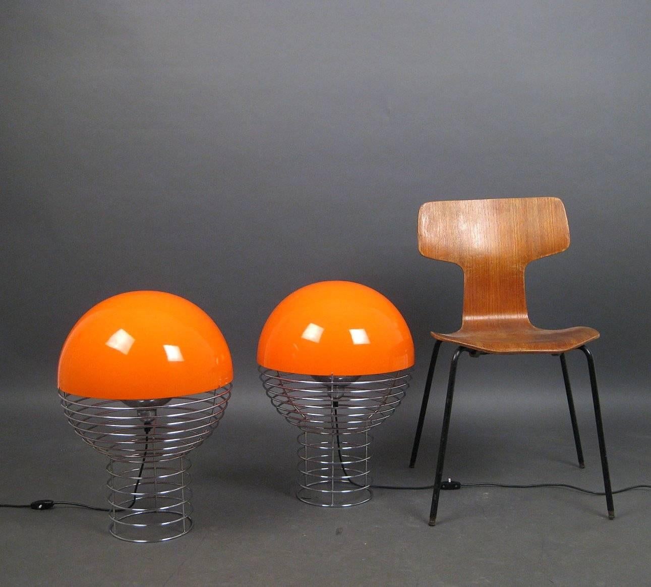 A pair of table lamps, model Wire Lamp, Danish design by Verner Panton for Lüber, Switzerland.
Structure with frame of chrome-plated steel wire, loose diffuser of orange plastic, white inside. Marked with pasted labels. 

 