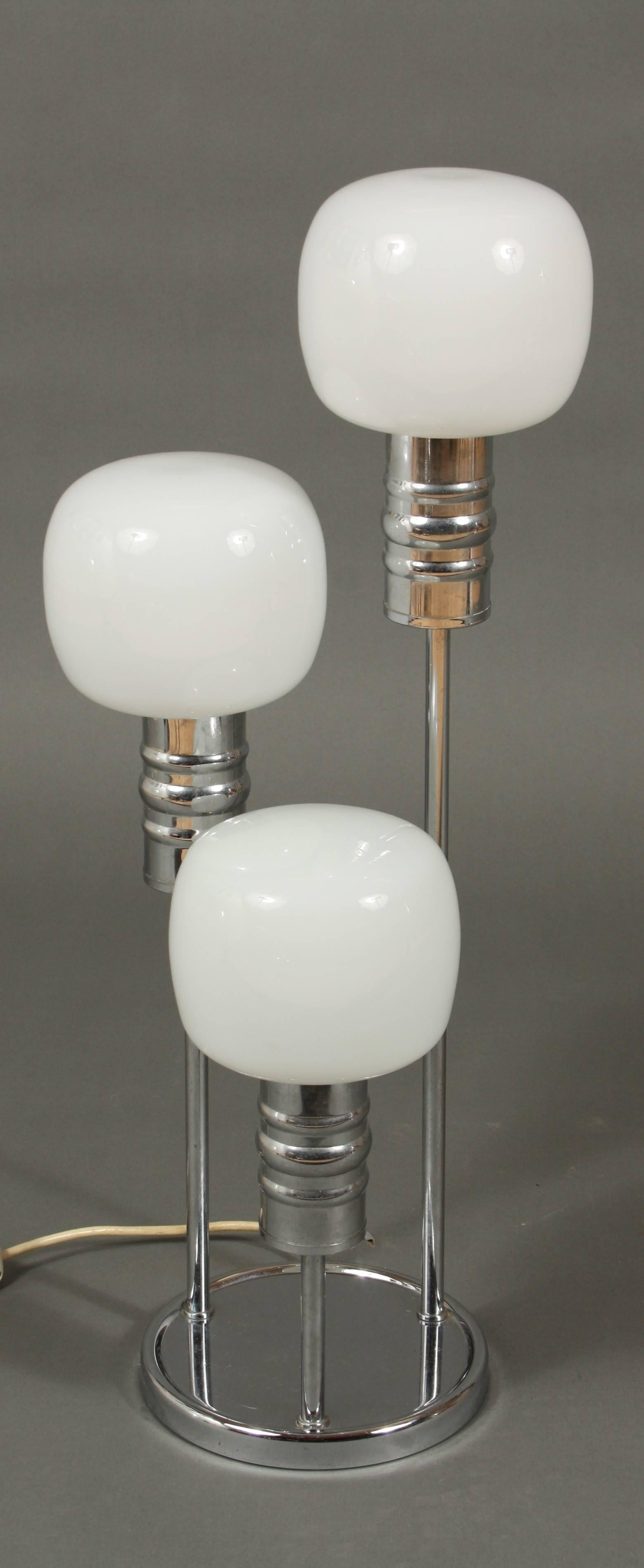 Chrome table lamp with three white glasses. The lamp is made of chrome-plated steel with three white milk-glass globes.

The table lamp lights with three bulbs and has an on/off switch.

 