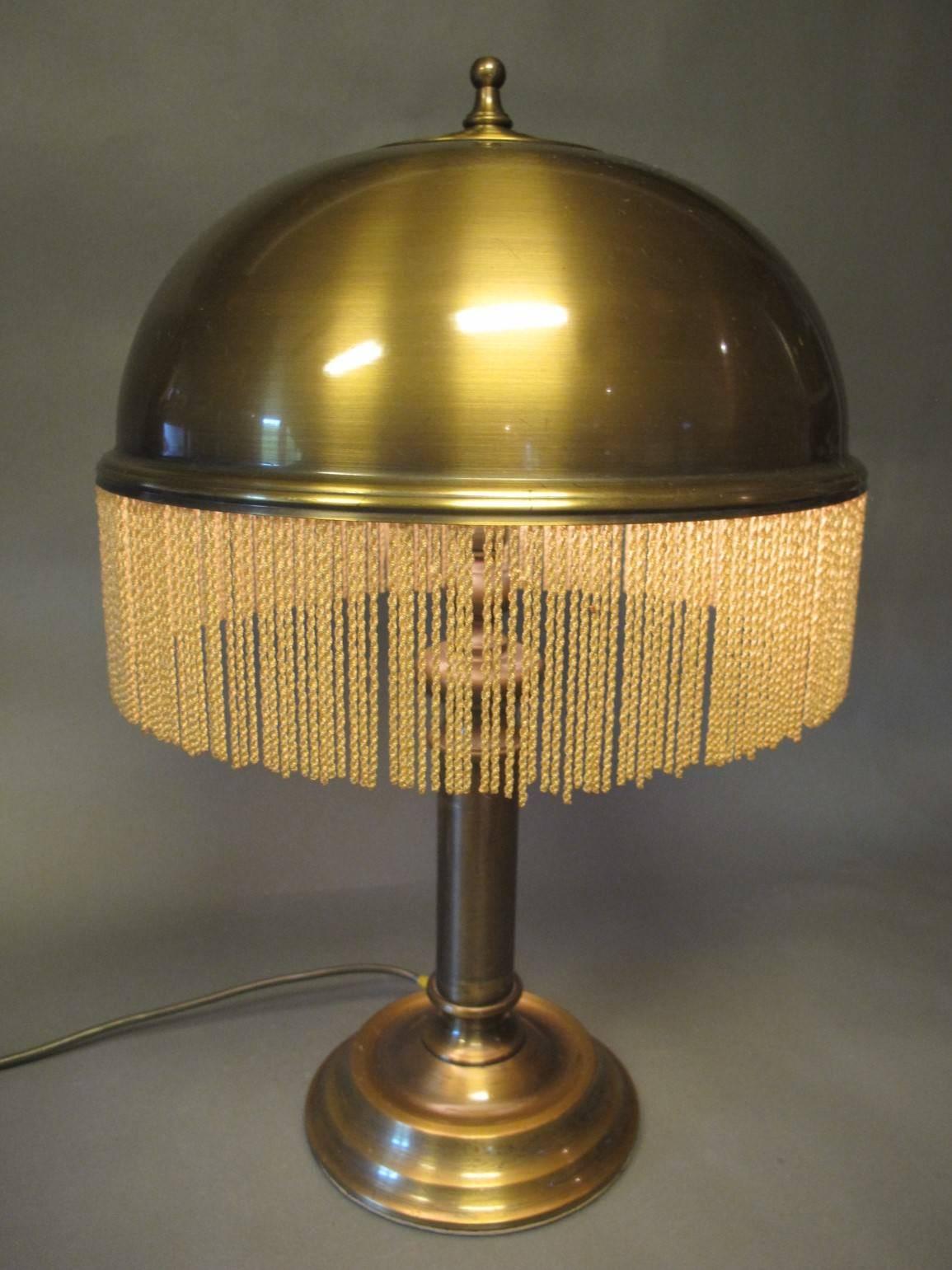 Art Deco table lamp brass and fringe. It has two bulbs. The lamp leaves a soft and beautiful light on the surroundings. The lamp has some marks from use, but very original and beautiful.