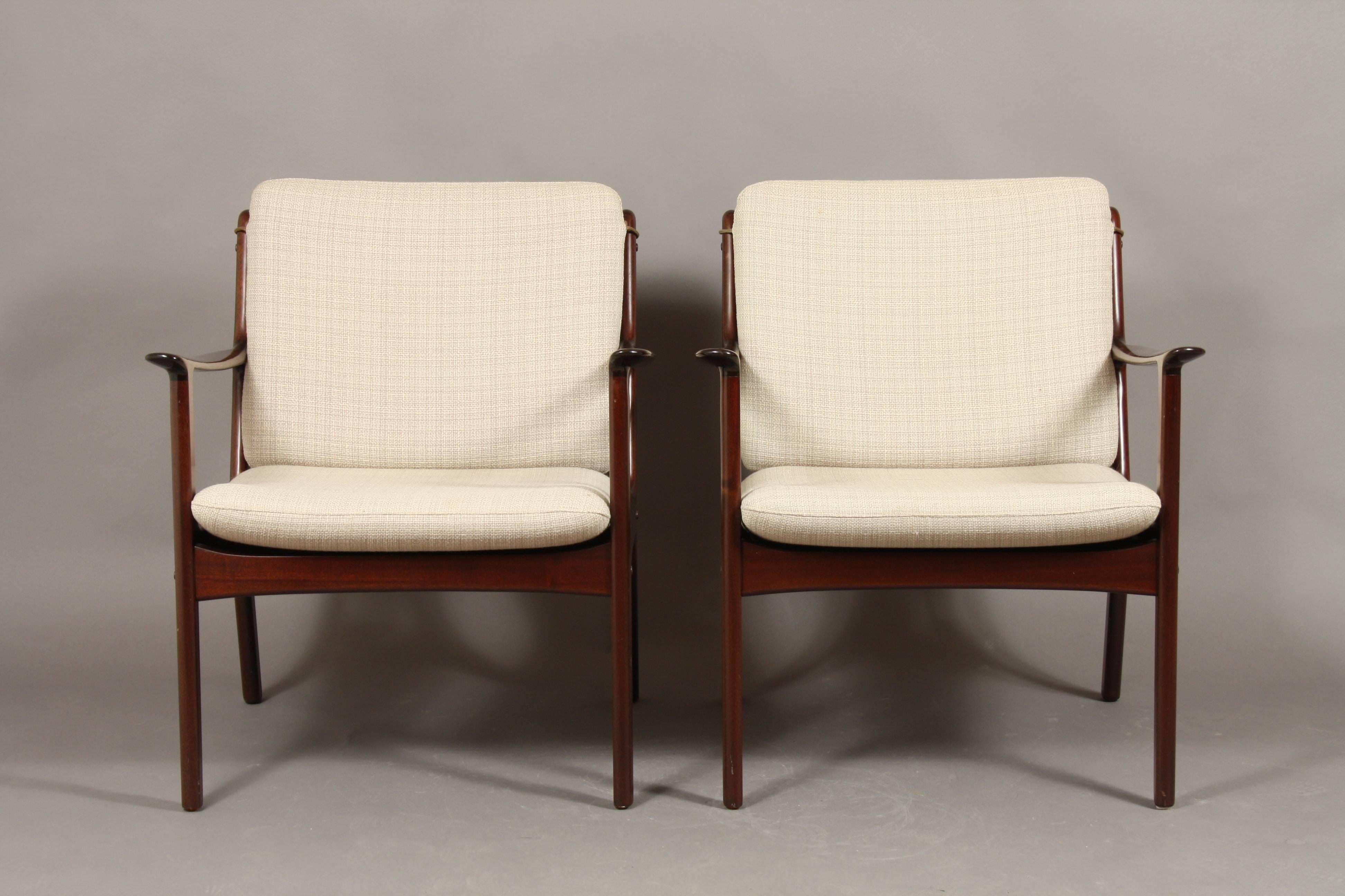 Classic Ole Wanscher design. Pair of easy chairs model PJ 112 designed in 1951 and produced by P. Jeppesen Møbelfabrik. Marked at the bottom with Danish Design mark and PJ mark. Original cushions in light wool, with leather straps. Very good