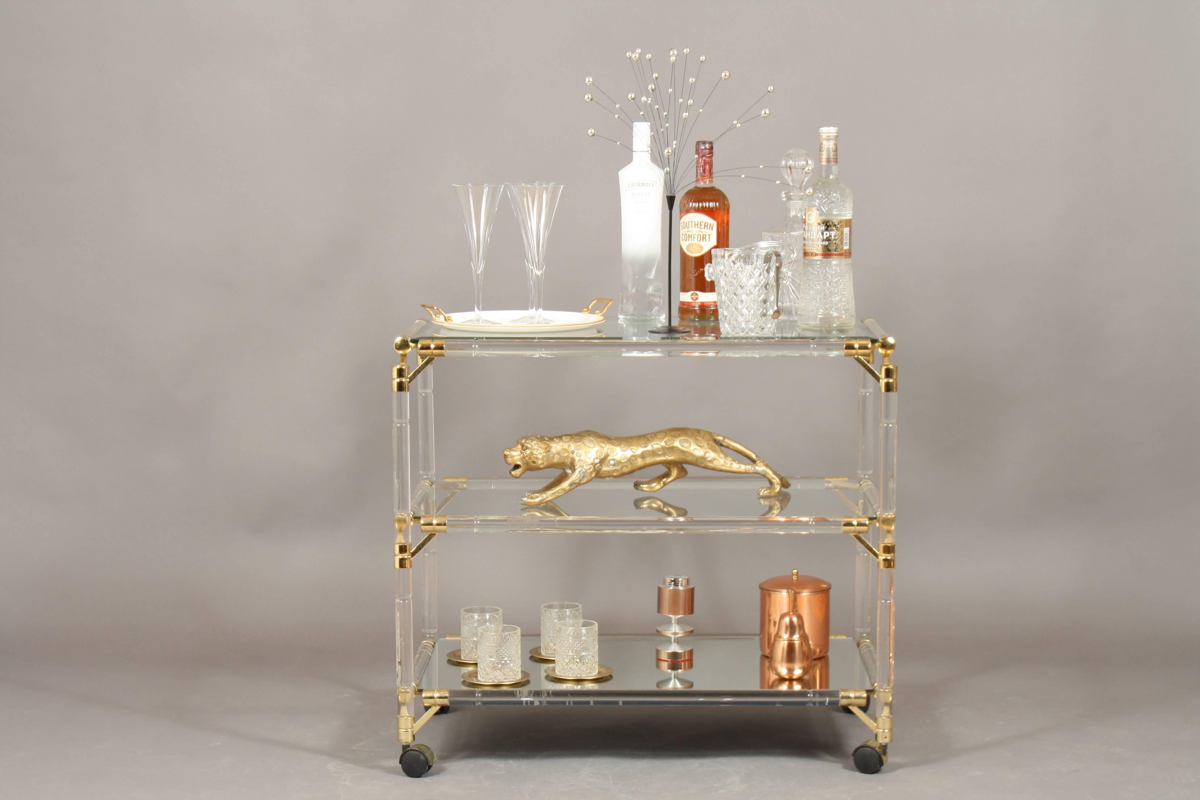 Drinks trolley, glass, mirror, Lucite and gilt, Italy. A stylish drinks trolley. There is only some minor wear here and there. The glass on the top glass is faceted, heavy and beautiful. At the bottom there is mirror.
