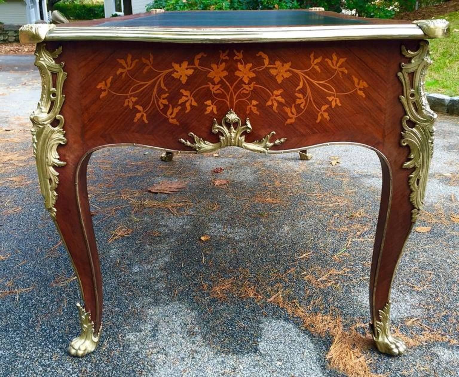 This kingwood Louis XV style bureau plat/writing desk has finely executed tulipwood marquetry of flowers and leaves. 
The ormolu mounts are all original and so is the almost black and green leather top. Constructed with highest quality, the