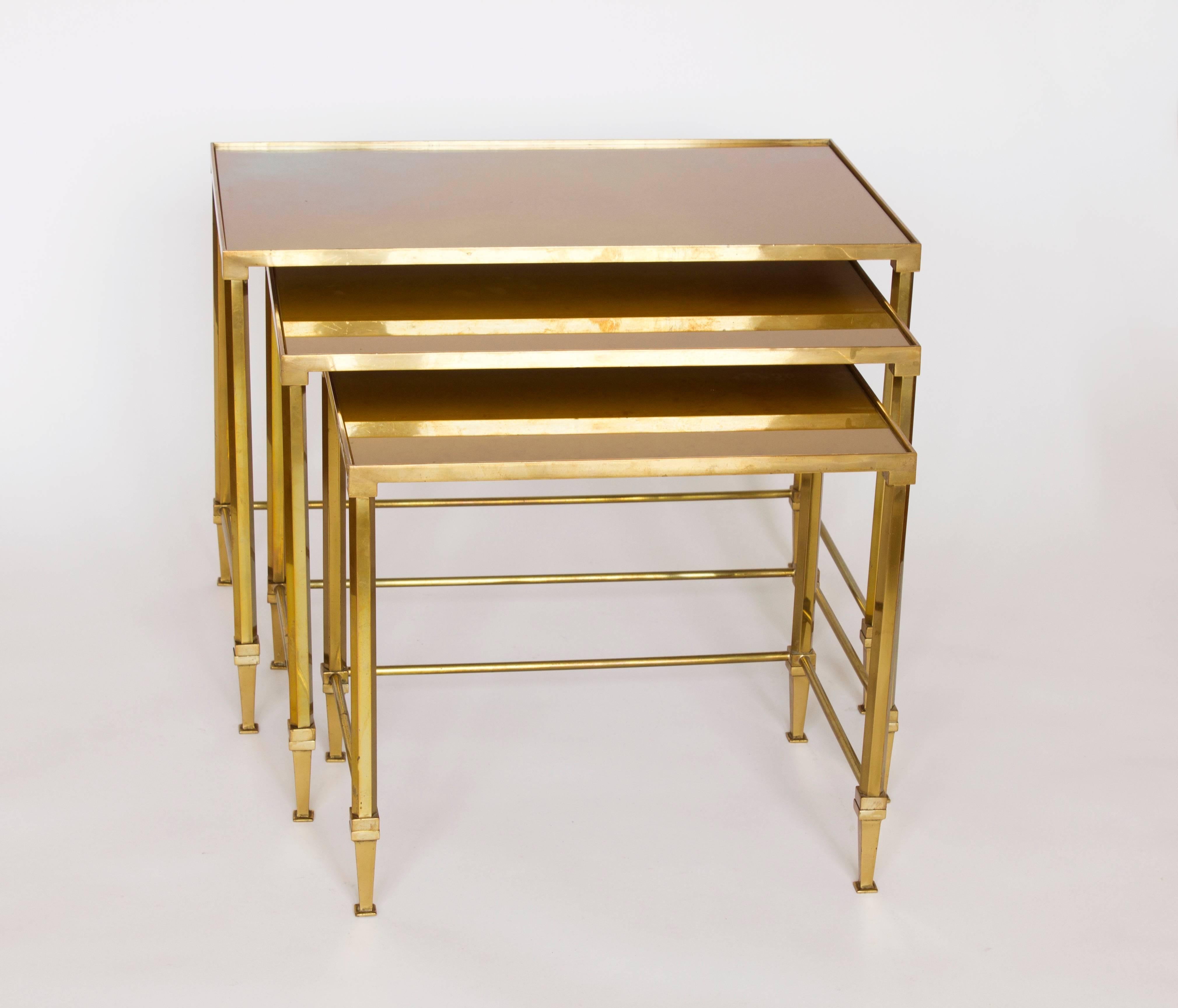 France, 1950s. From Maison Jansen.
Beautiful ensemble of brass nesting tables with patinated ochre-gold mirrored top.
With modern neoclassical feel.
Very good condition.

H x W x D
Large table: 41 cm x 55 cm x 33 cm
Middle table: 38 cm x 47 cm x 30