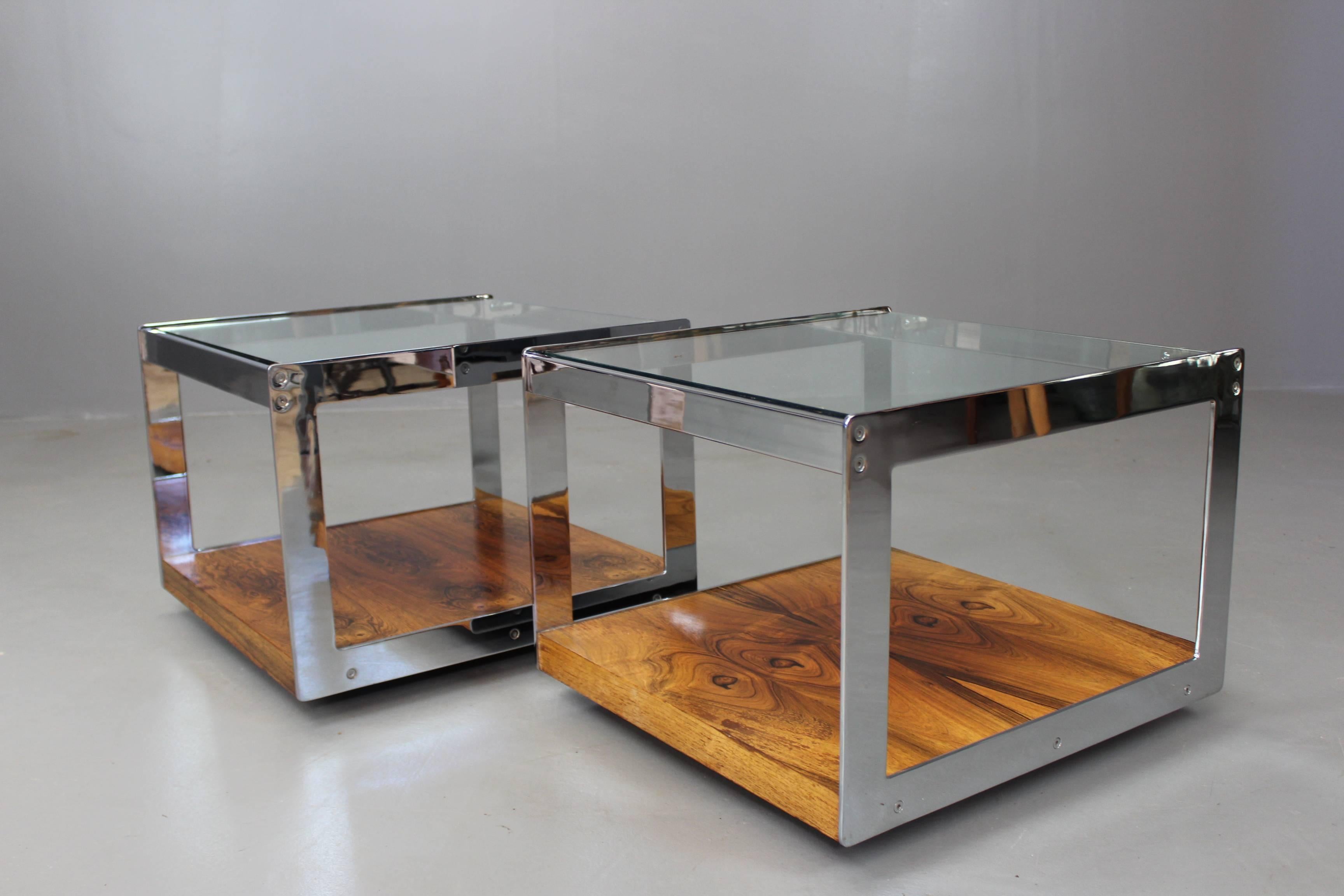Lovely pair of Merrow Associates coffee tables. Pair of quality retro tables, designed by Richard Young, chrome-plated square frame with rosewood veneer lower tier and drop in thick glass top on castors.

The combination of rosewood, chrome and
