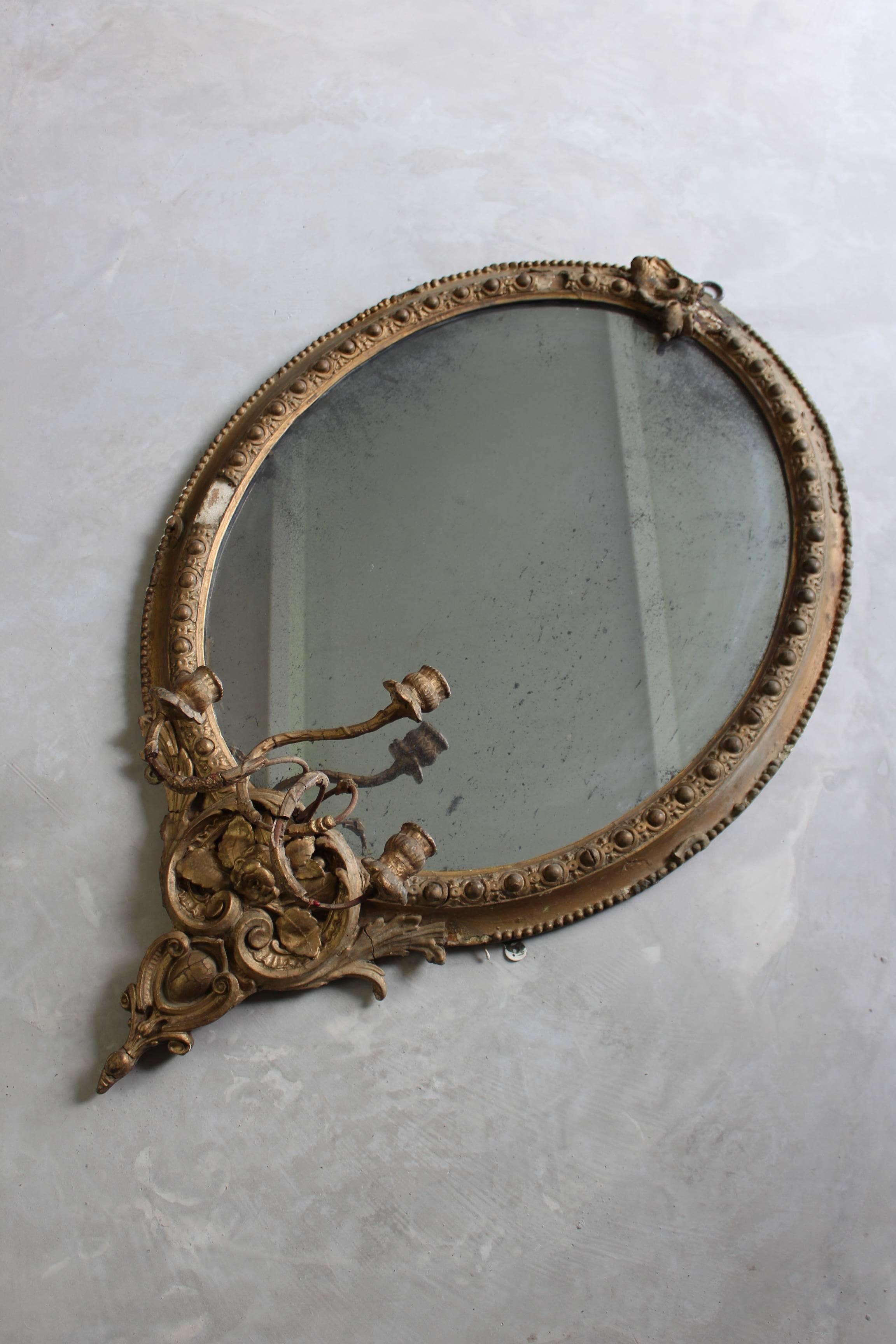 Antique gilt girandole mirror. Large early 19th century gilt gesso girandole oval mirror. The mirror is heavily foxed.

Please click our logo for more items, and to see our full inventory.