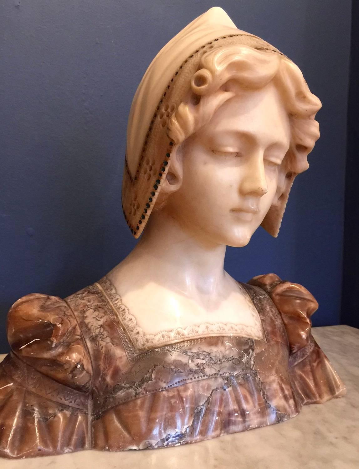 An exquisite Italian alabaster bust of a young maiden wearing a bonnet, with painted highlighted detail. Good contrast of color and fine detail. Beautiful carving to the bonnet and dress especially the lace detail. The dress with its puffed sleeve