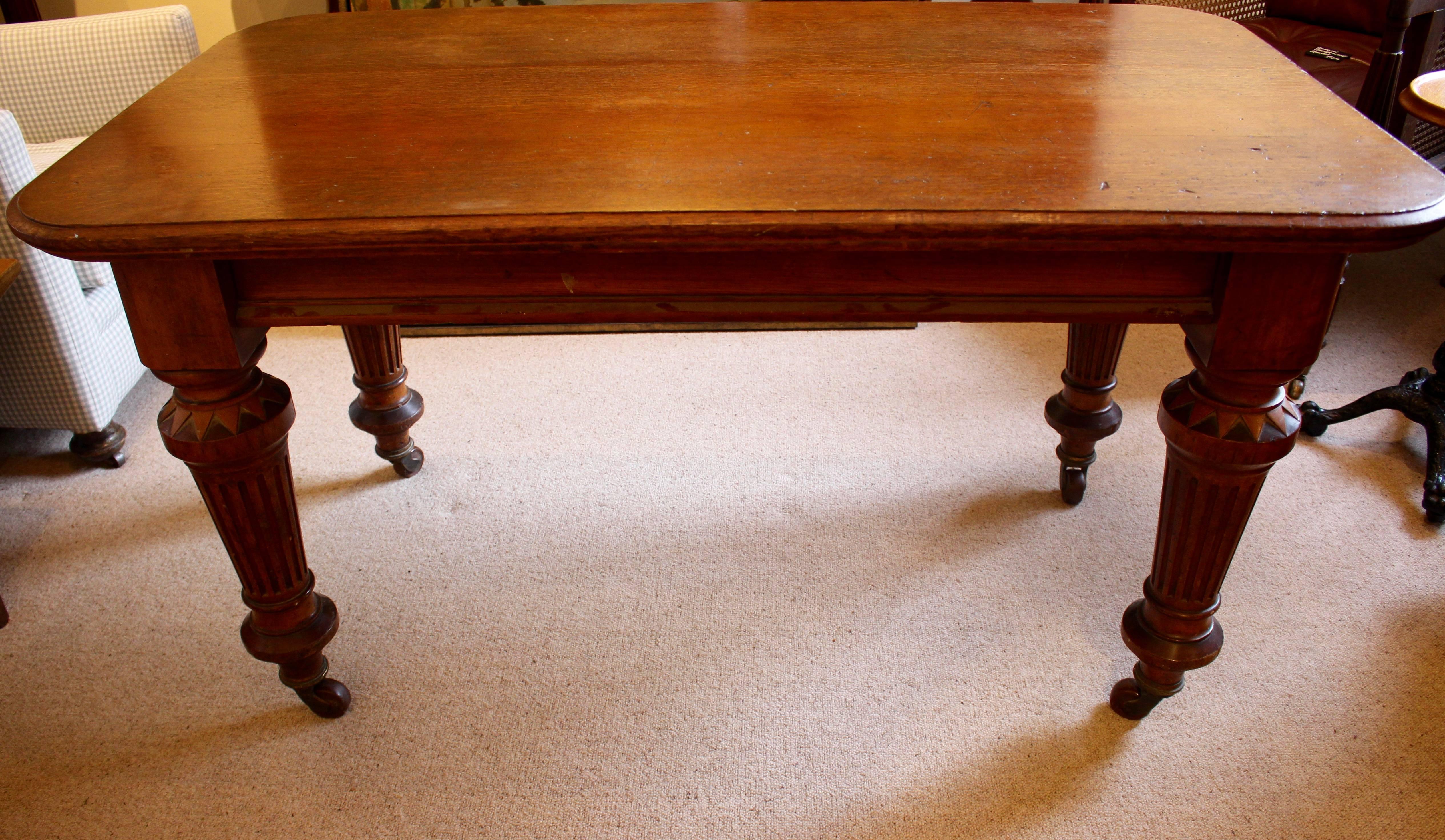 A handsome Victorian Oak Library table. Having lipped edge tabletop with rounded corners. The most delightful legs, being topped with a circular cambered top and attractive dogs tooth carving. The main part of the leg being tapered and fluted, with