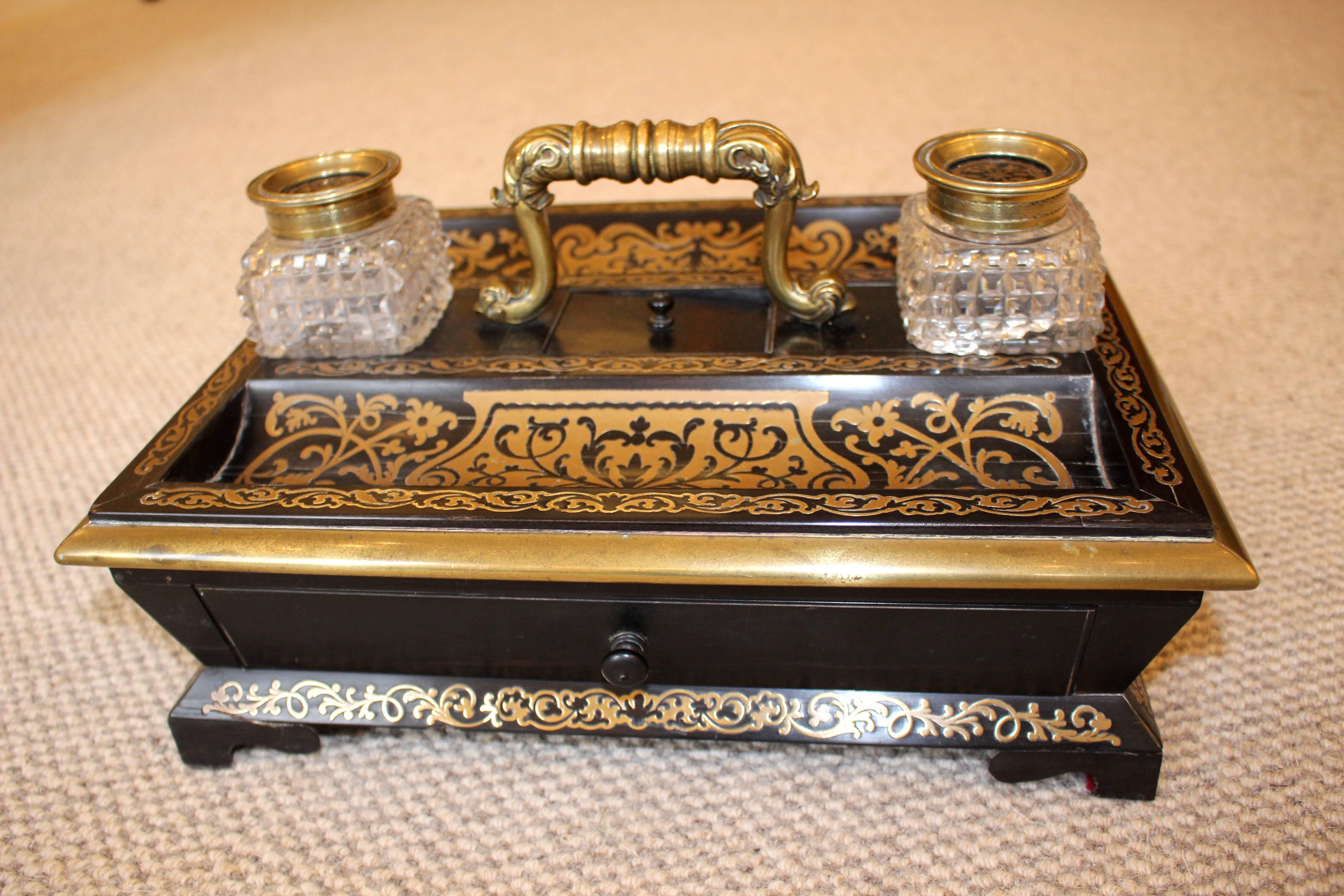 Here we have a highly decorative and beautifully made mid 19th Century Ebony and Boulle Inkwell or Desk Stand. Having two cut glass inkwells with tooled brass lids with central brass decoration. Front and rear pen trays with a small central lidded