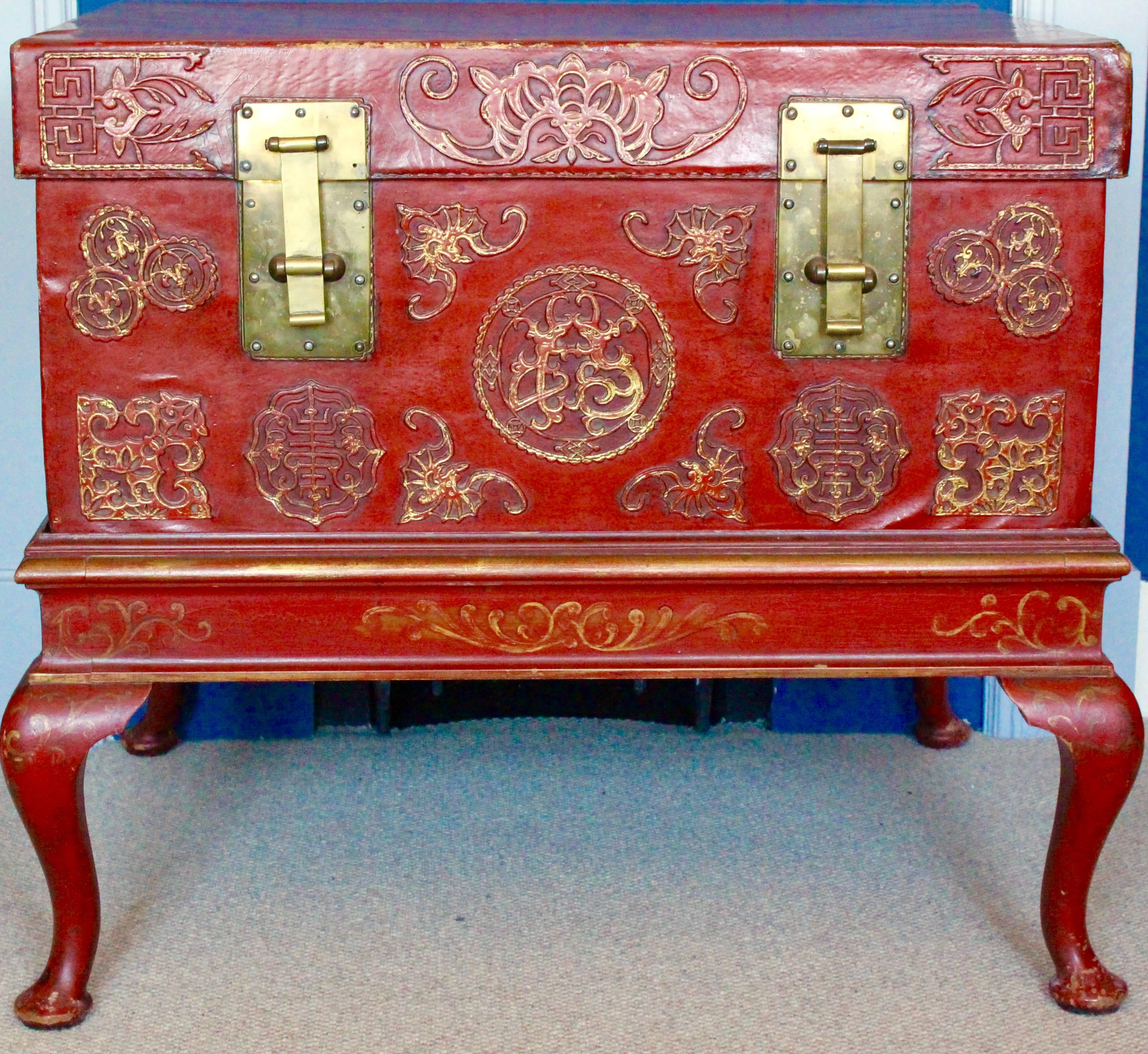 A highly decorative pair of Chinese red leather trunks. Each finished in a red lacquer, richly decorated with auspicious symbols in gilt highlight, the bats and Shou characters believed to bring good fortune and longevity. Each trunk has brass