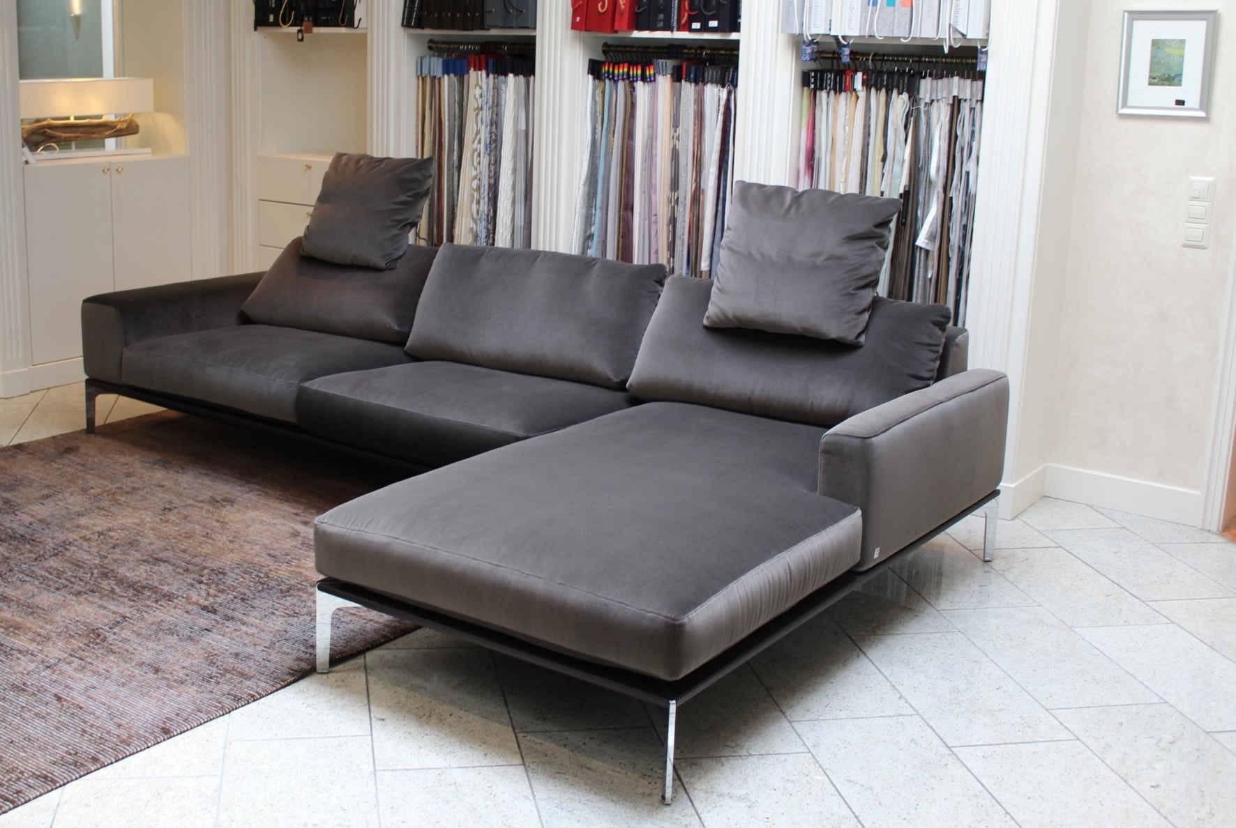 This corner sofa has a fabric covering and has a wooden base with a leather covering. Its covering is shimmers brown-grey and is in excellent condition. It comes from one of our well curated showrooms in Germany.