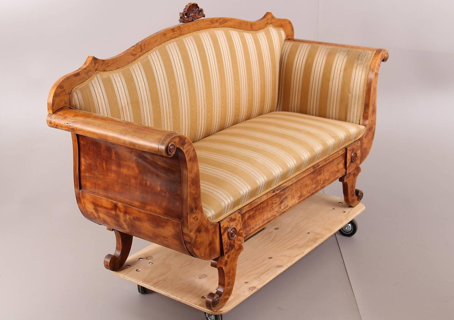 Antique Swedish Biedermeier empire smaller sofa with a highly carved shape and stunning shell motif on the top.

There are smaller carved details above the gracefully curved legs and roundels on the end of the swooping arms.

The sofa features the