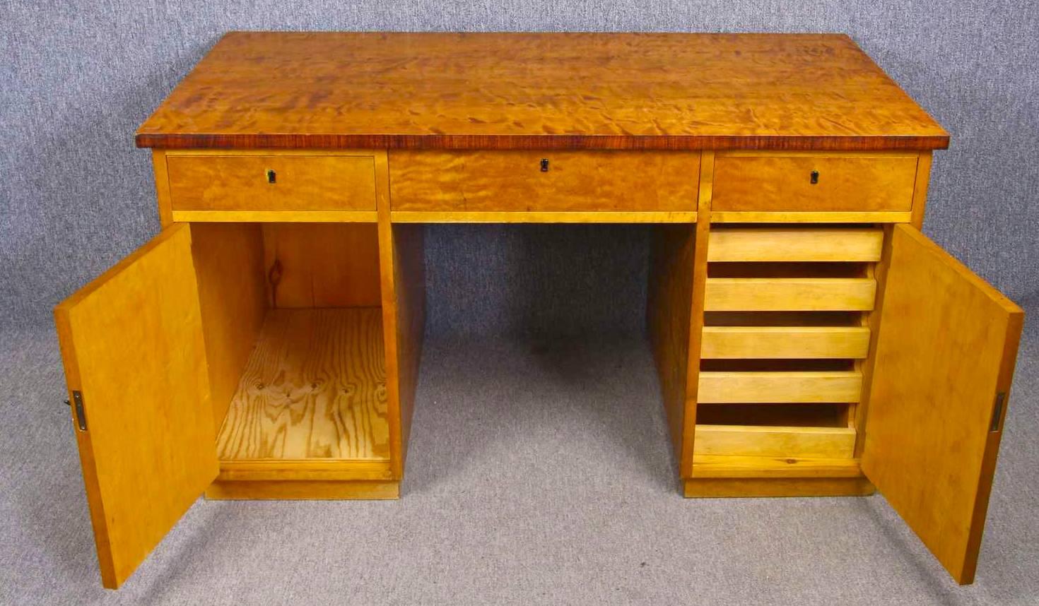 Rare antique Swedish Art Deco pedestal partners desk with the finest grade of quilted golden birch veneers in a classic honey color French polish finish.

The desk has three main drawers, space for shelves in the left hand pedestal and six pullout