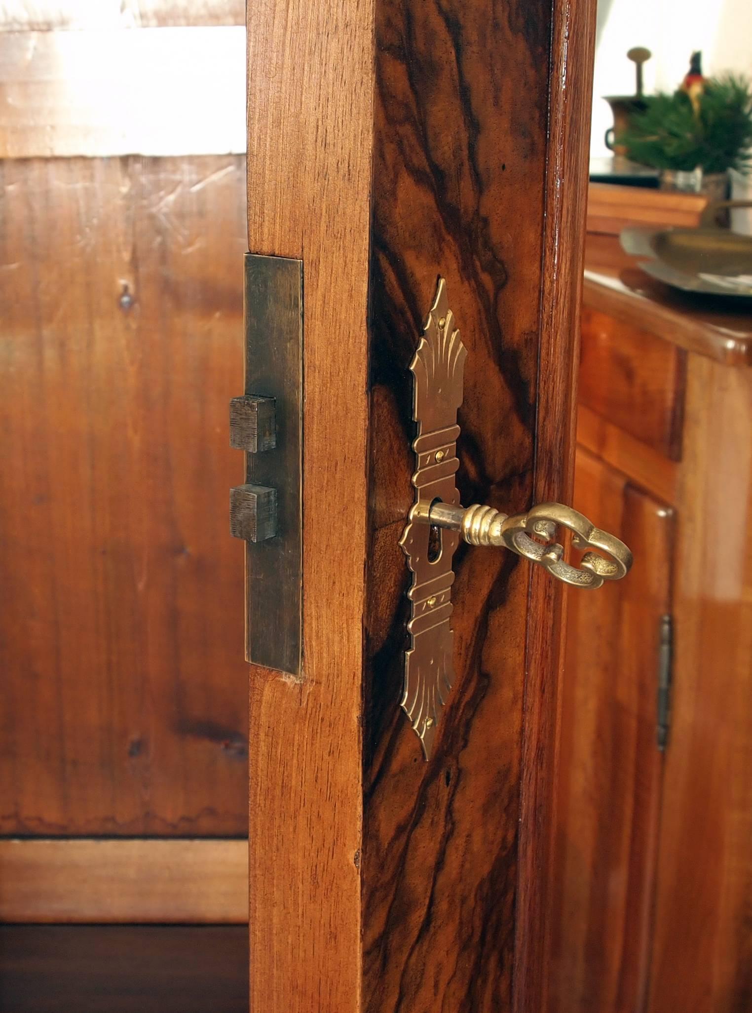 The walnut armoire having a single mirror door with adjustable internal shelves above a drawer. The shelves are not available, but these are will be made from pine wood according to your wish. The walnut veneer has a pinewood body.