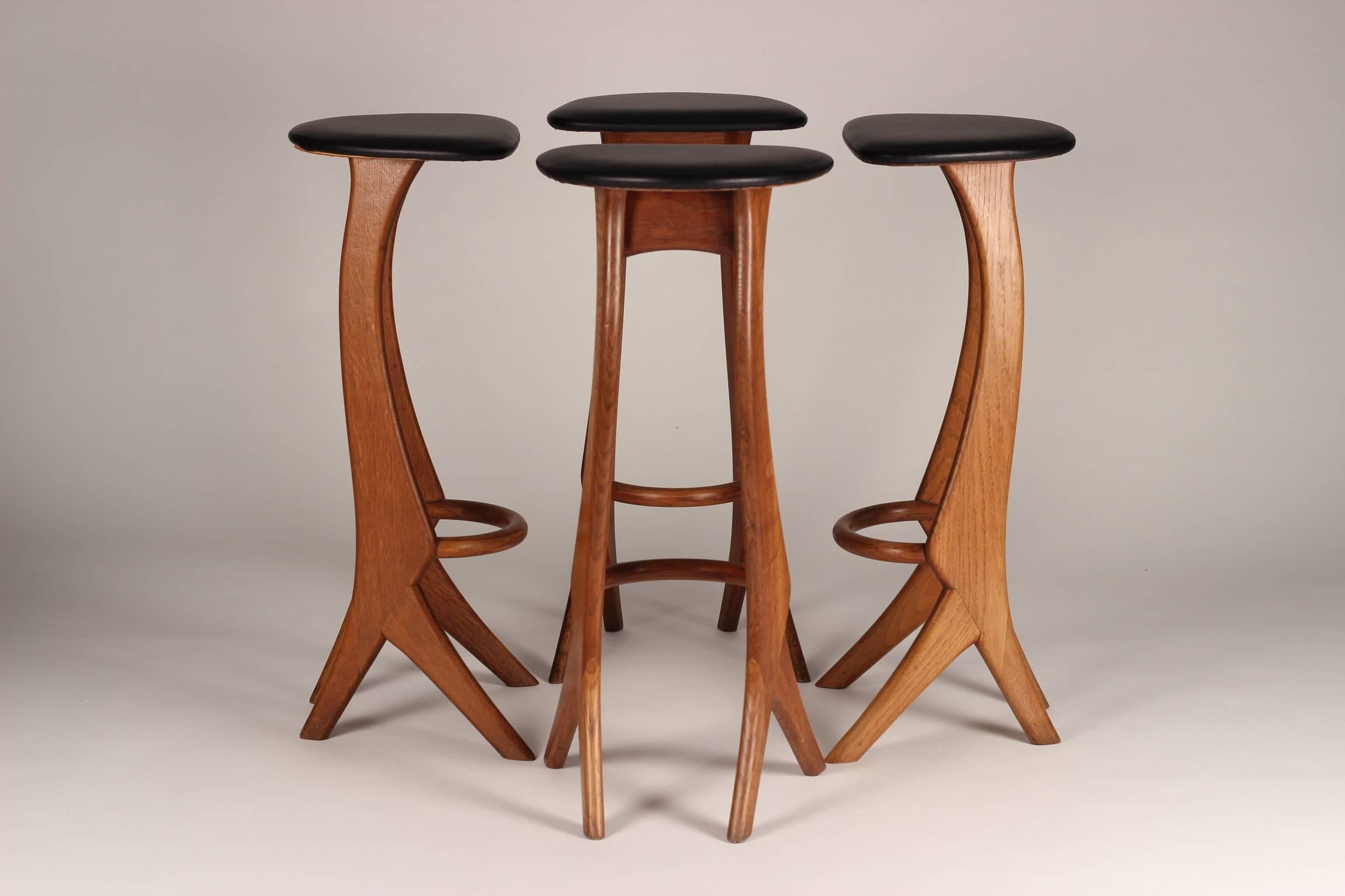 A rare and beautiful organically shaped set of four 1960s barstools by Reyway. With sculptural solid teak restored bases and reupholstered black leather seats.
