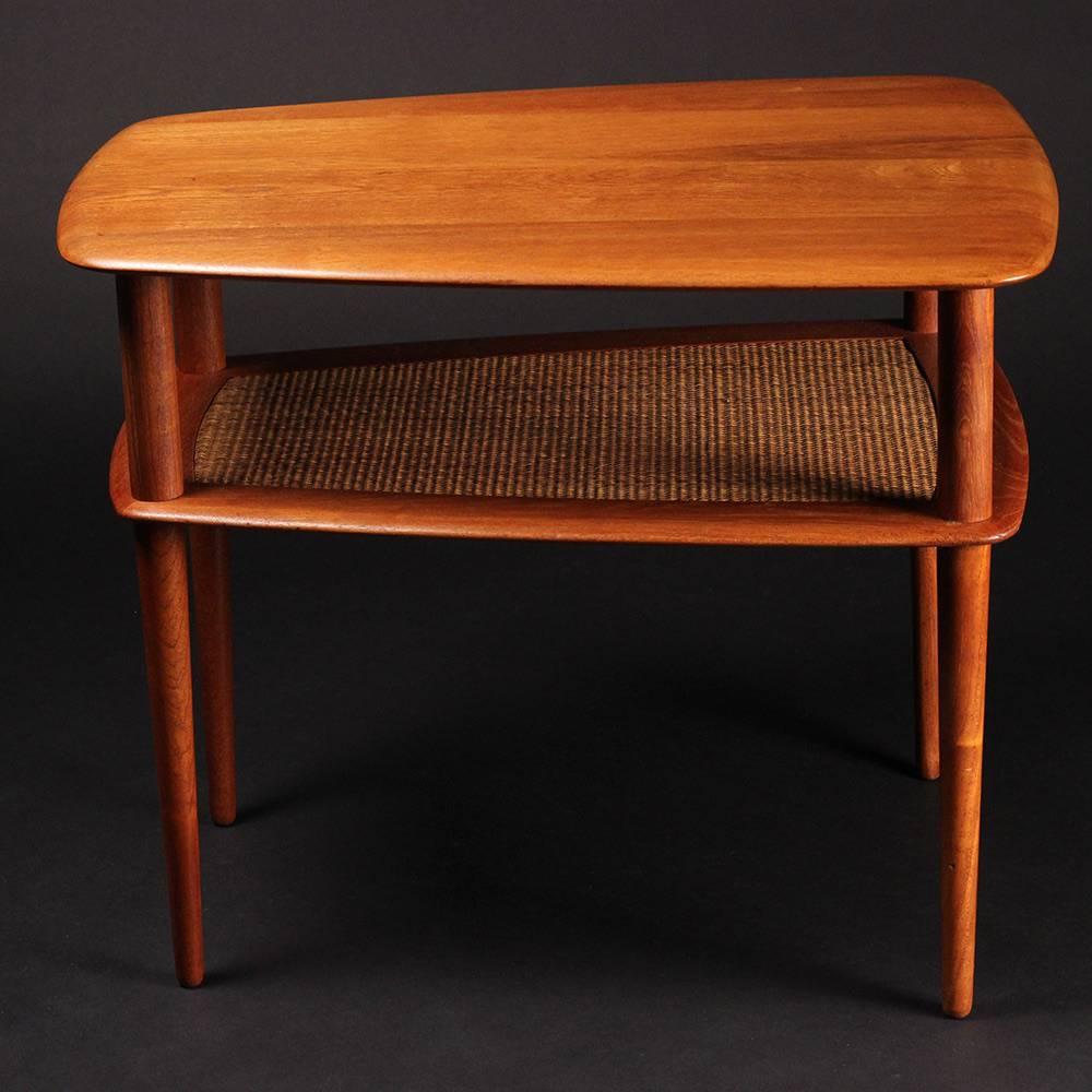 A restored and in excellent condition, solid teak and caned two-tiered end or side table. Bearing makers mark verso.