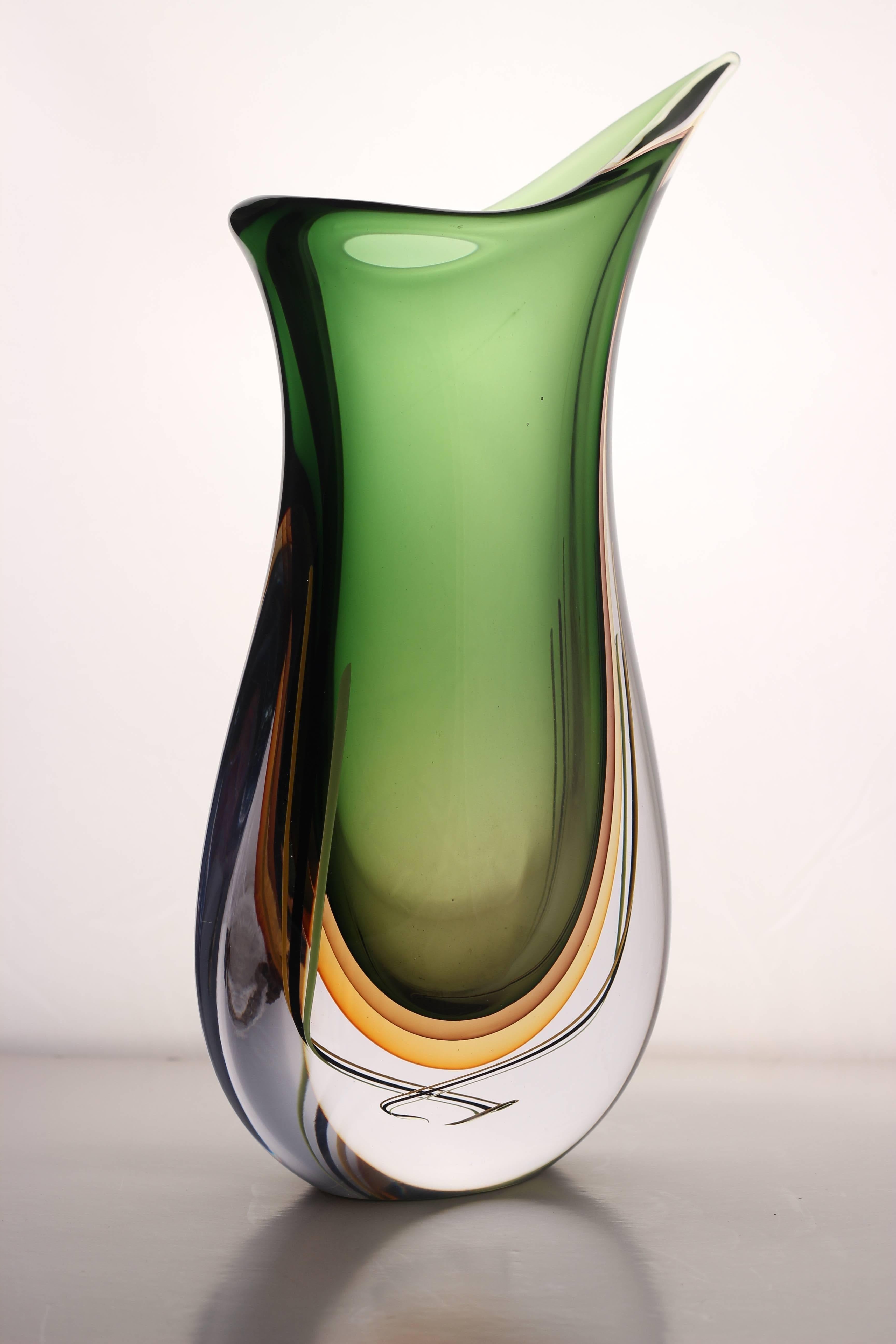 This vessel has a style called ‘submerged‘ because it has been created using solid shapes within solid glass and is therefore particularly heavy. The technique used for this vase involves capturing the shadow of the vessel within itself. Signed to