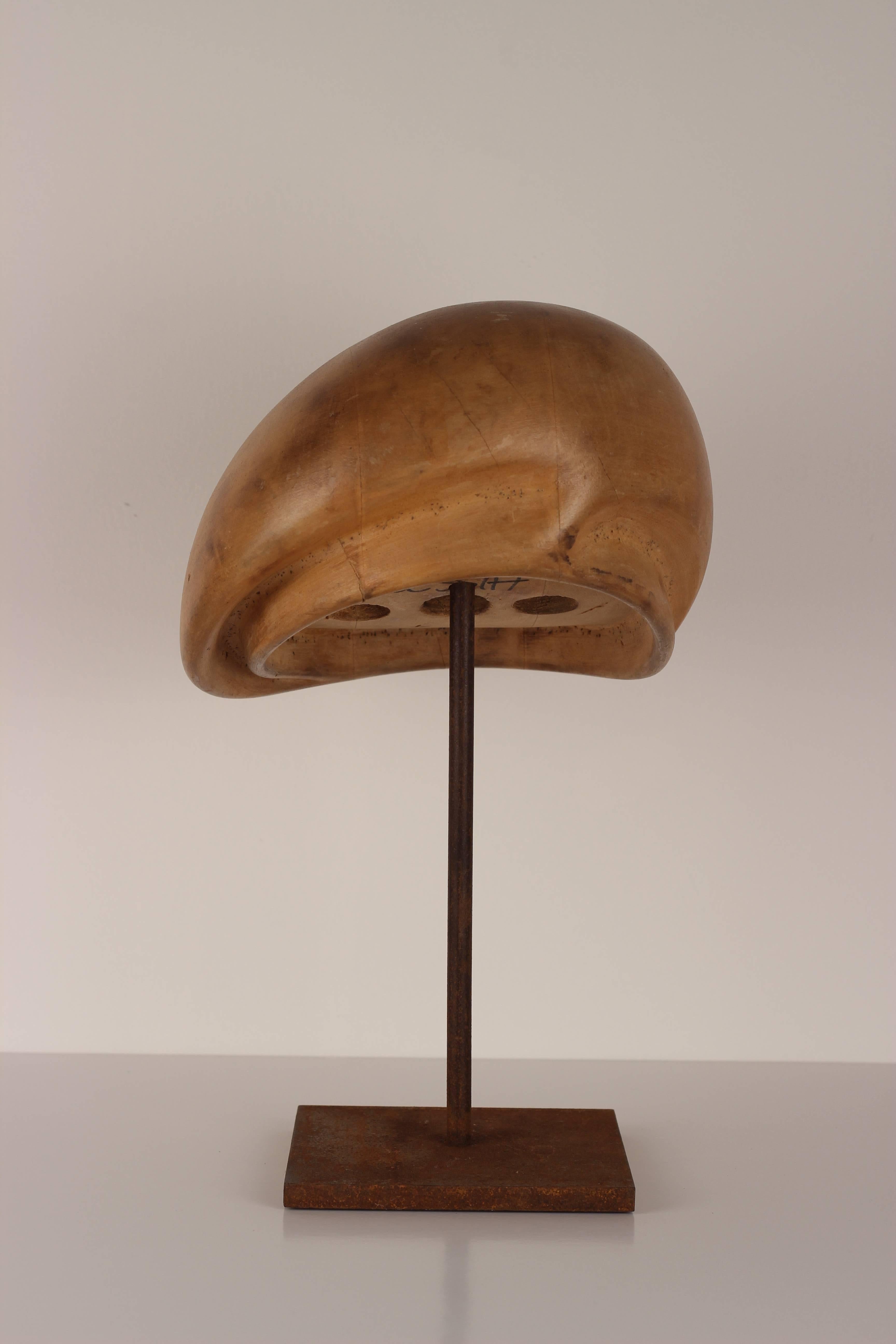 One of a collection of sculptural looking milliner wooden hat blocks from the well-known hat makers of Florence. The hat block is mounted on a metal oxidised stand.
