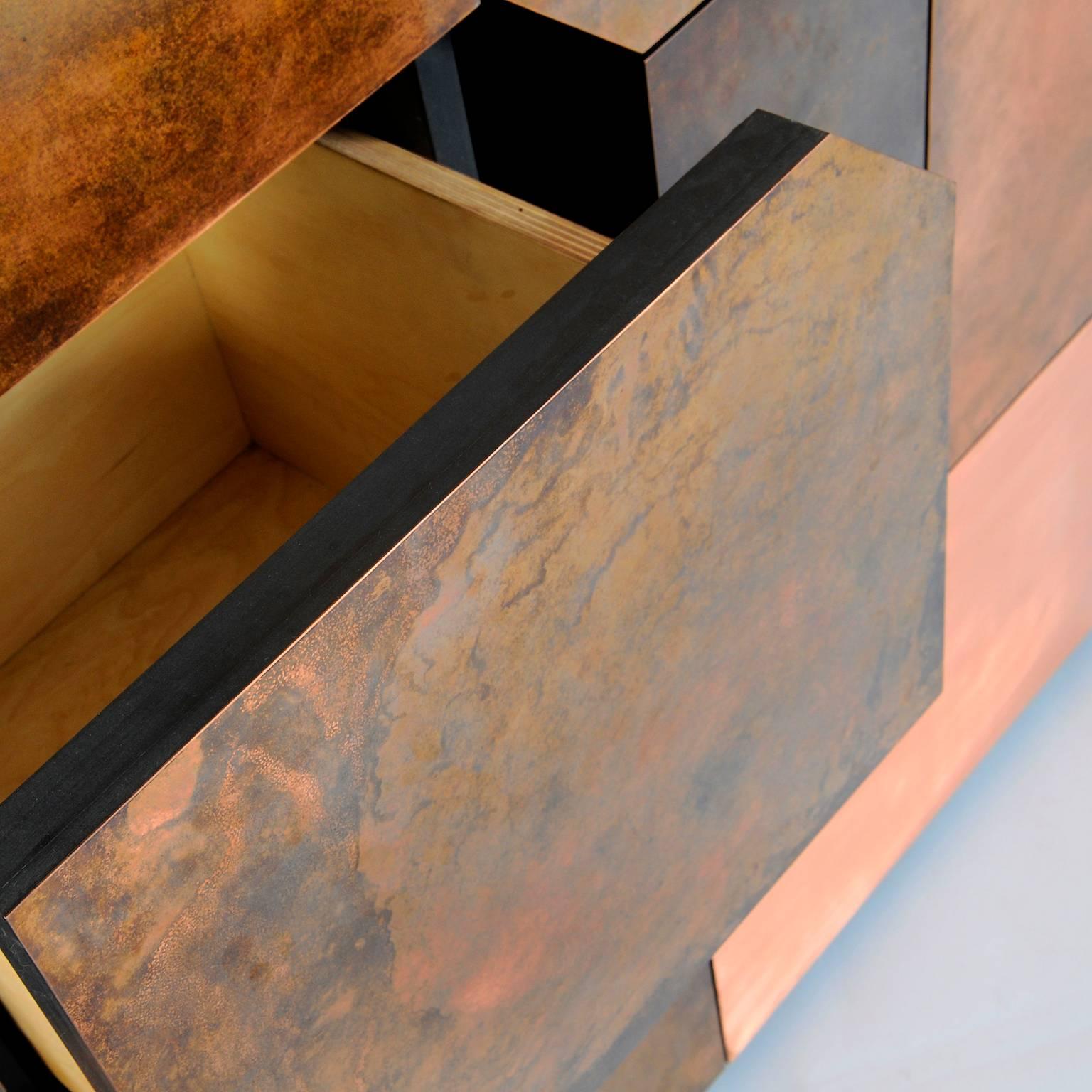 The Elementi copper patina cabinet is a monolithic, rough and challenging piece of sculptural furniture. Clad with copper sheet patina mosaic which disguises two cupboards and five drawers behind it.

Available to order in a number of different