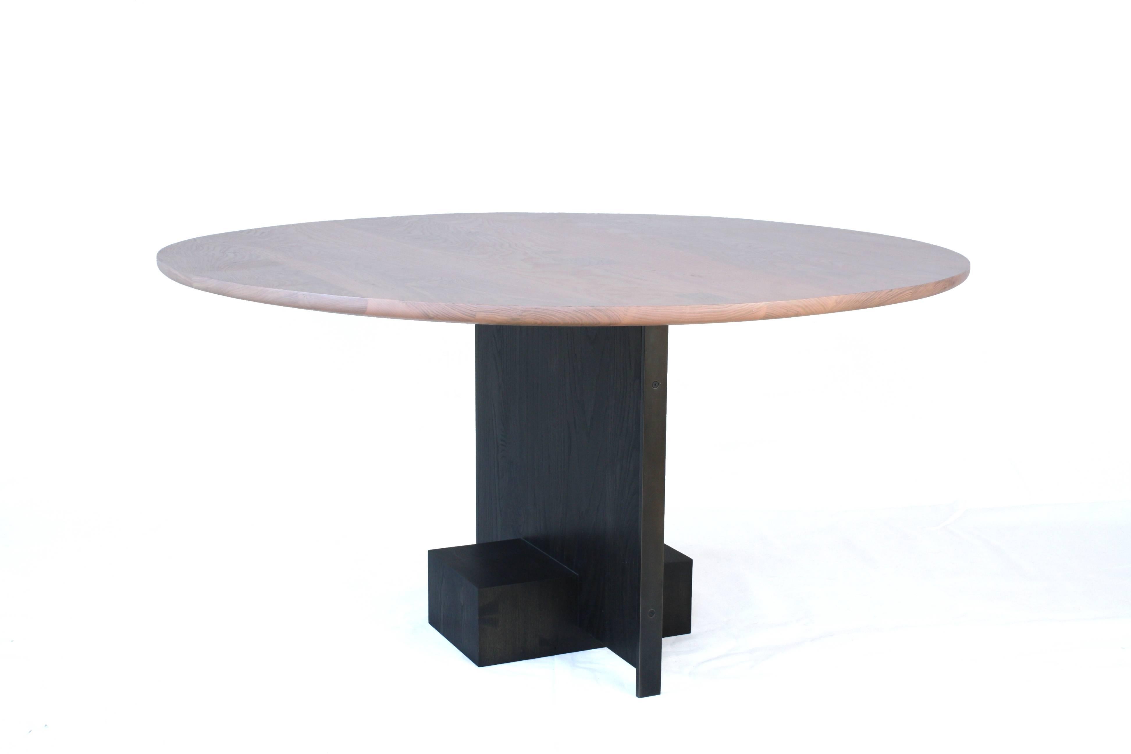 Handmade in Chicago by Laylo Studio, this dining table can be customized for any space.

Set into a solid wood end grain block, the panel leg of this table floats above the ground with the aid of a thick blackened steel bar running from the floor to